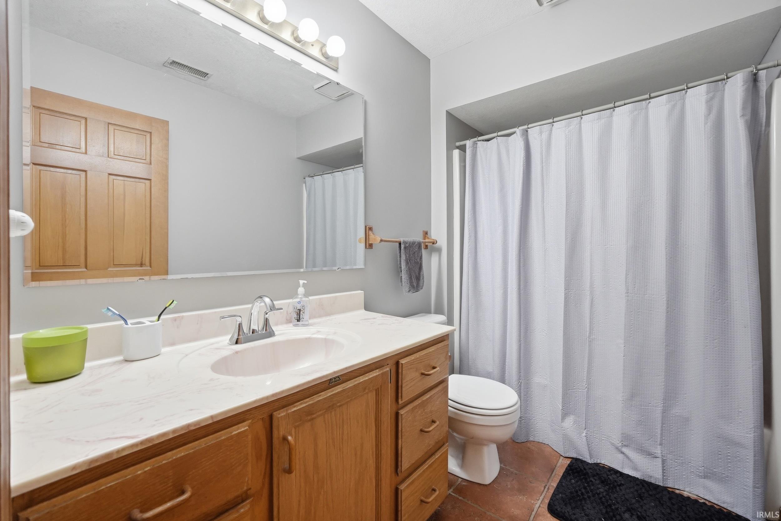Bathroom vanity featuring a light-toned countertop, integrated sink, and wood-finish cabinetry with drawer and cabinet storage
