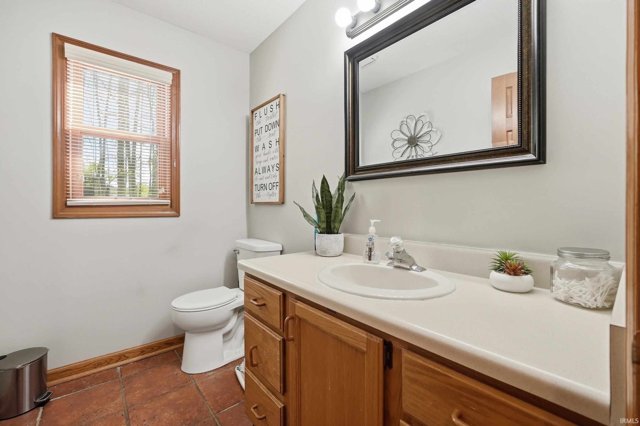 Bathroom vanity with a light-colored countertop, integrated sink, and wood-finish cabinetry
