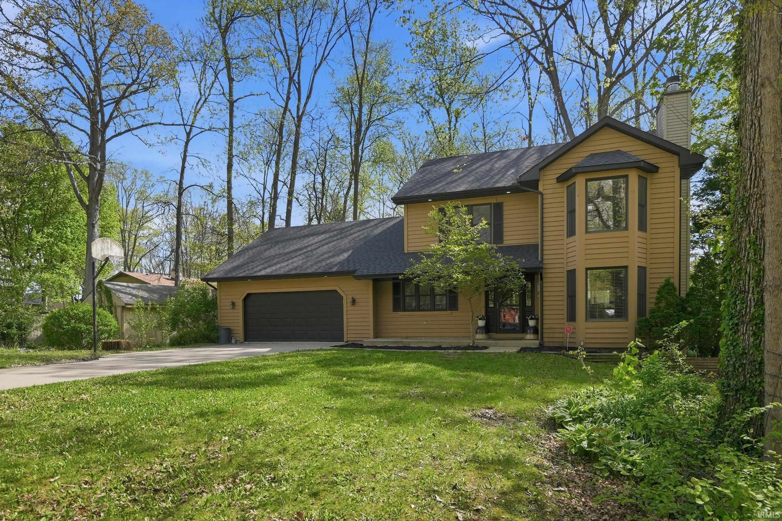 Two-story residence featuring a bay window, attached garage, and a concrete driveway