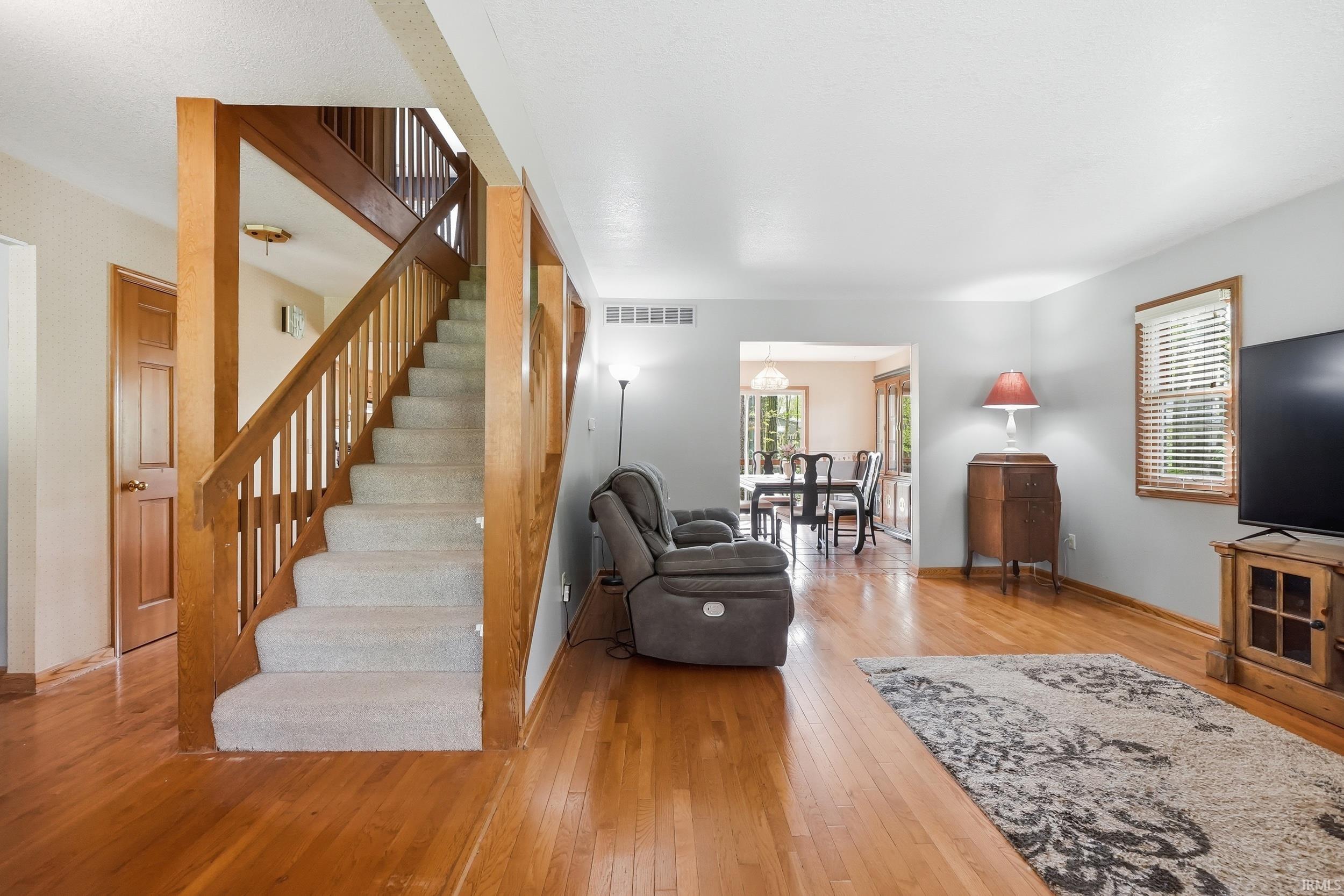 Hardwood flooring extends throughout the main living area, complemented by a carpeted staircase with wood banisters