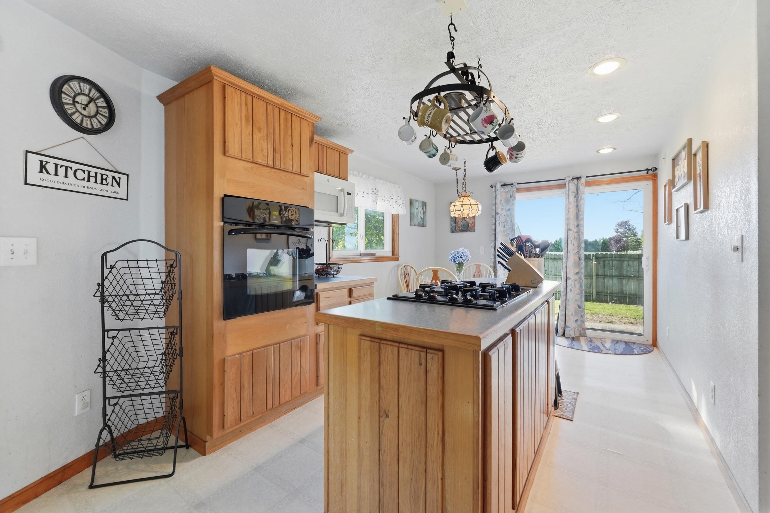 Kitchen featuring a built-in oven, wood-finish cabinetry, and a central island with an integrated cooktop