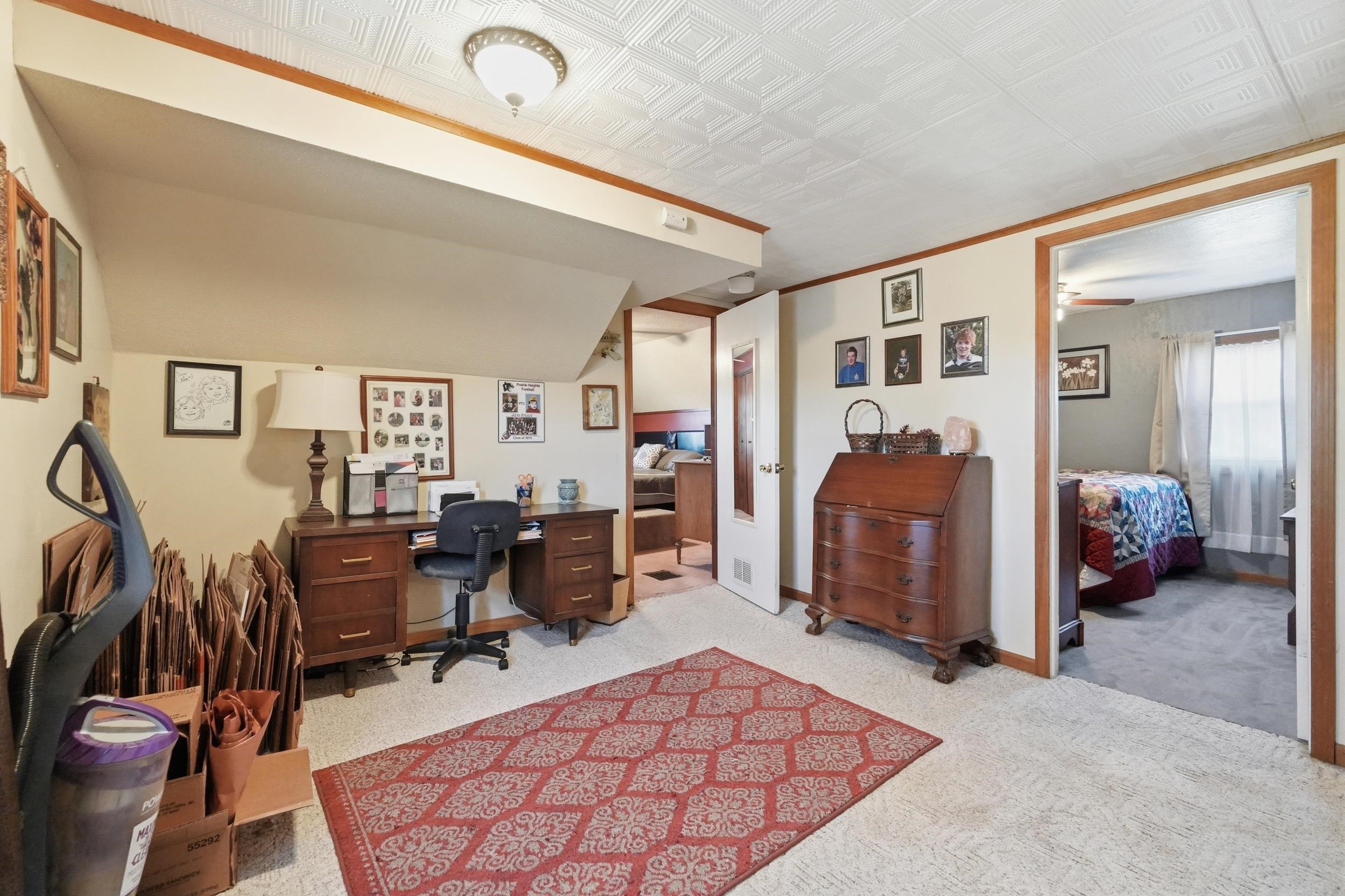 Carpeted room with a textured ceiling, featuring wood trim and a built-in ceiling light fixture