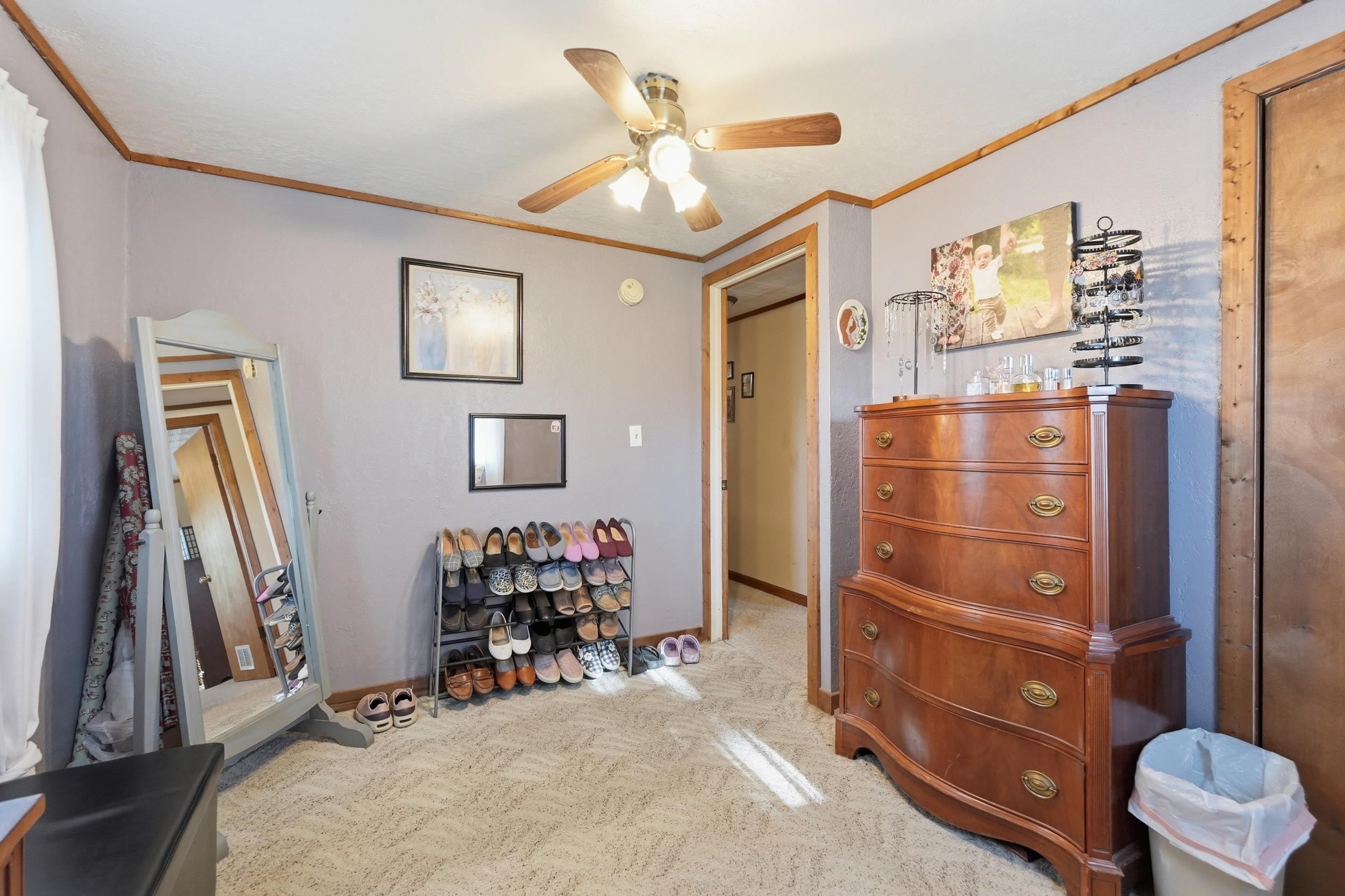 Carpeted room featuring a ceiling fan with integrated lighting, wood-trim baseboards, and a wood-trimmed doorway