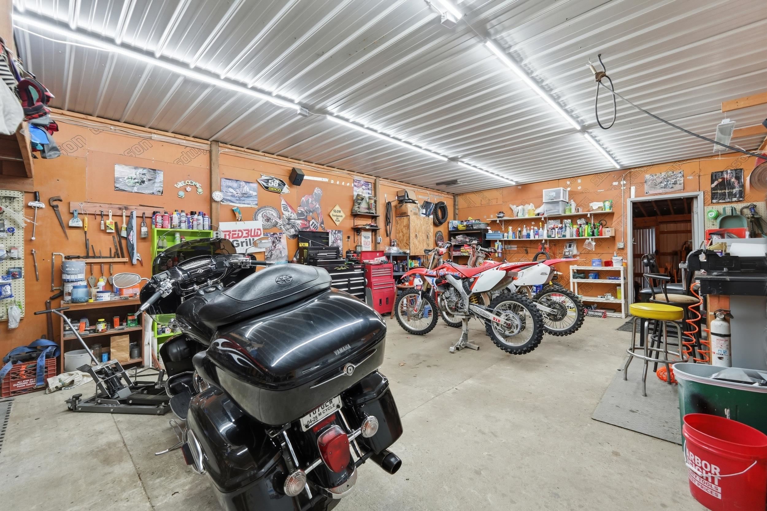 Spacious utility garage featuring concrete flooring, corrugated metal ceiling, and fluorescent strip lighting