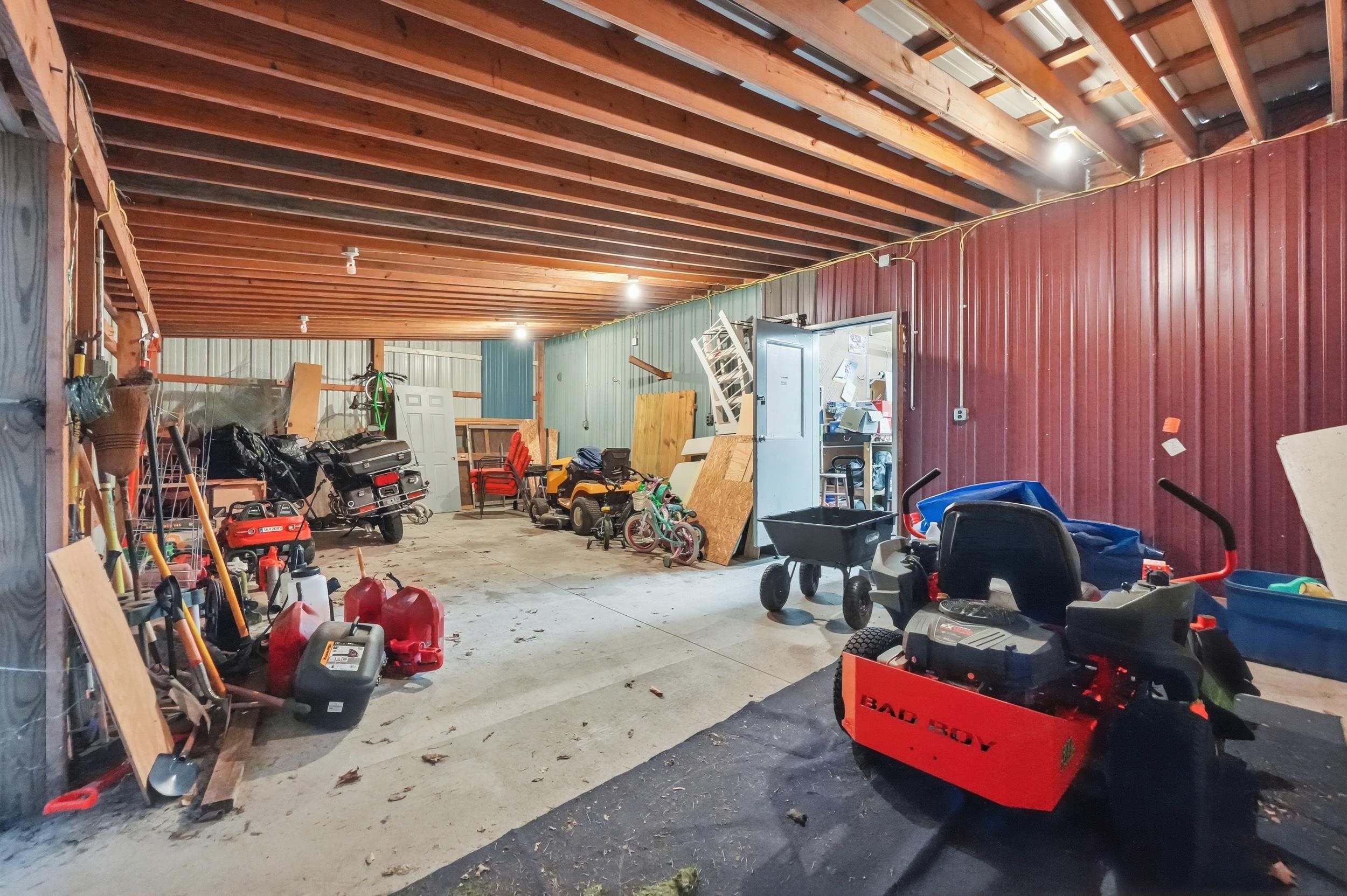 Spacious utility building with exposed wood ceiling joists, concrete flooring, and corrugated metal walls