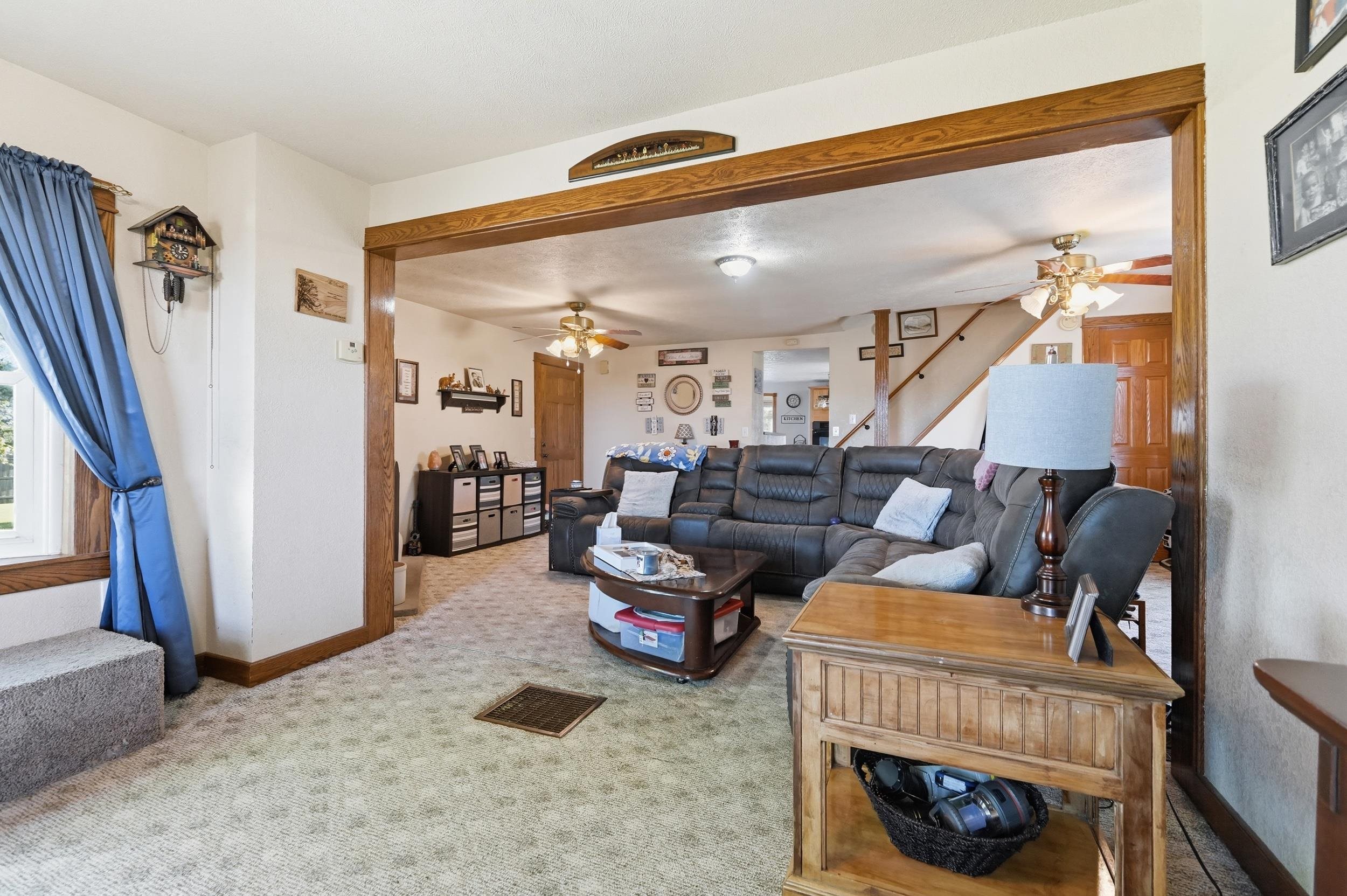 Spacious living area featuring light-toned patterned carpet and white walls