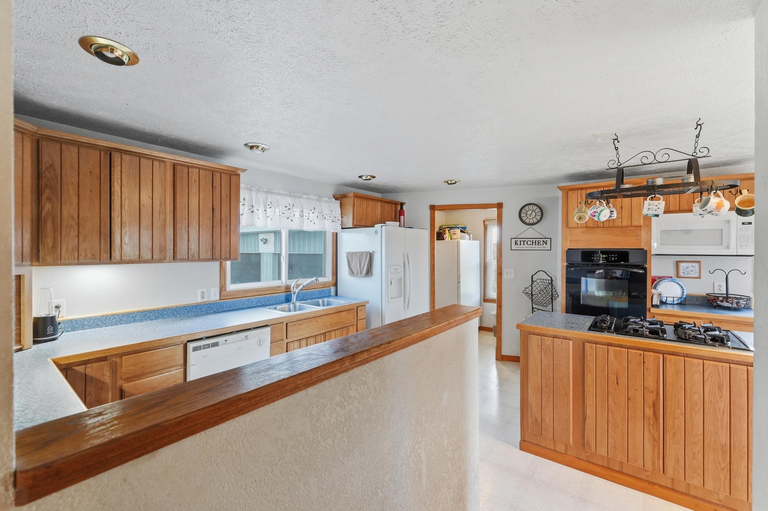 Kitchen featuring wood cabinetry, light blue countertops, a built-in oven, and a gas cooktop