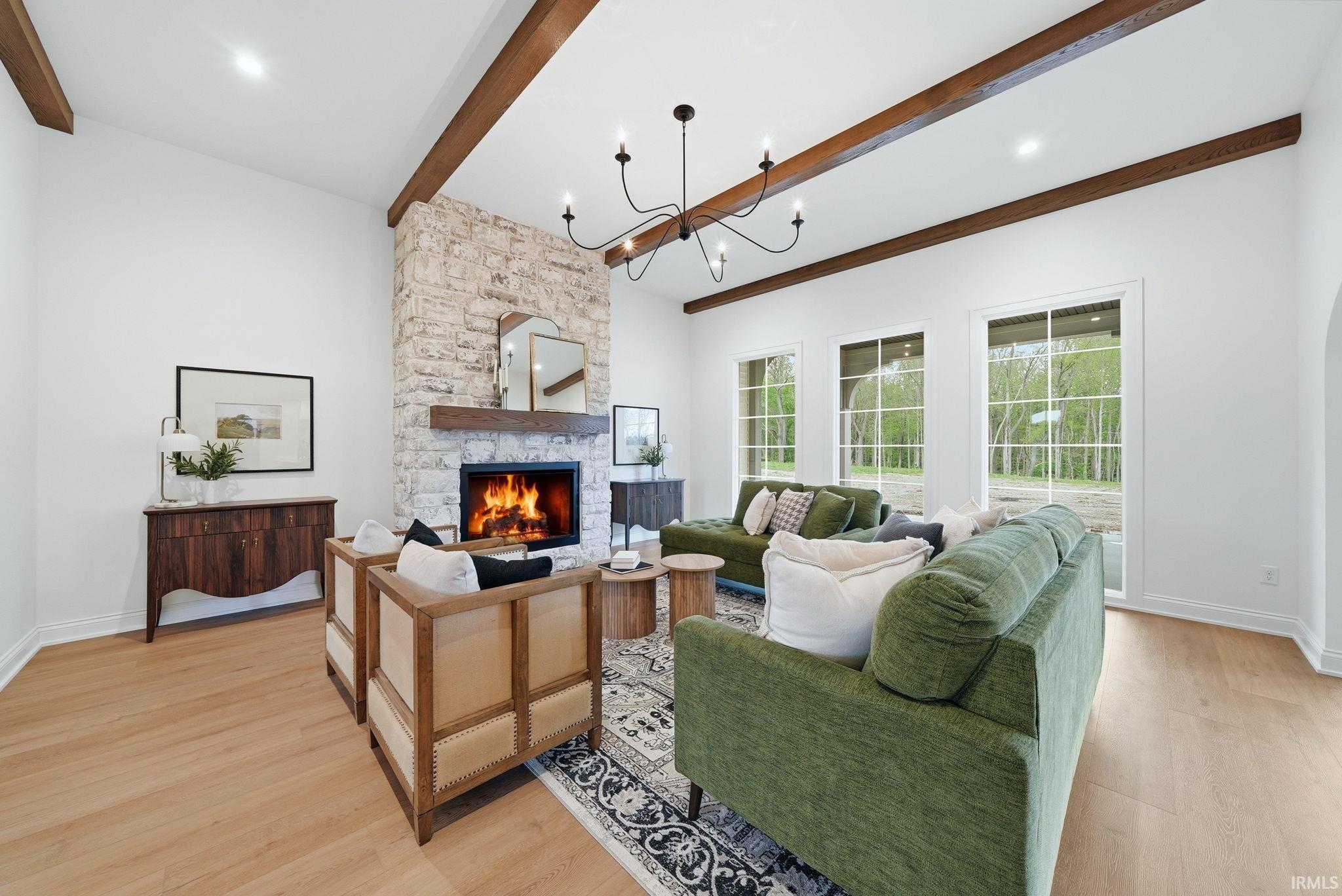 Living area featuring a stone fireplace with a wood mantel, wood-finish flooring, and exposed ceiling beams