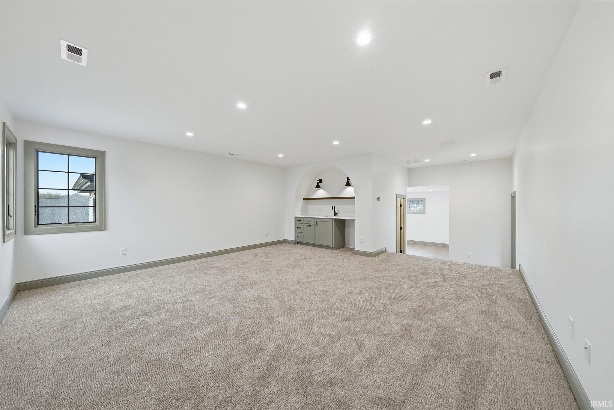 Spacious room featuring neutral carpet flooring and white painted walls