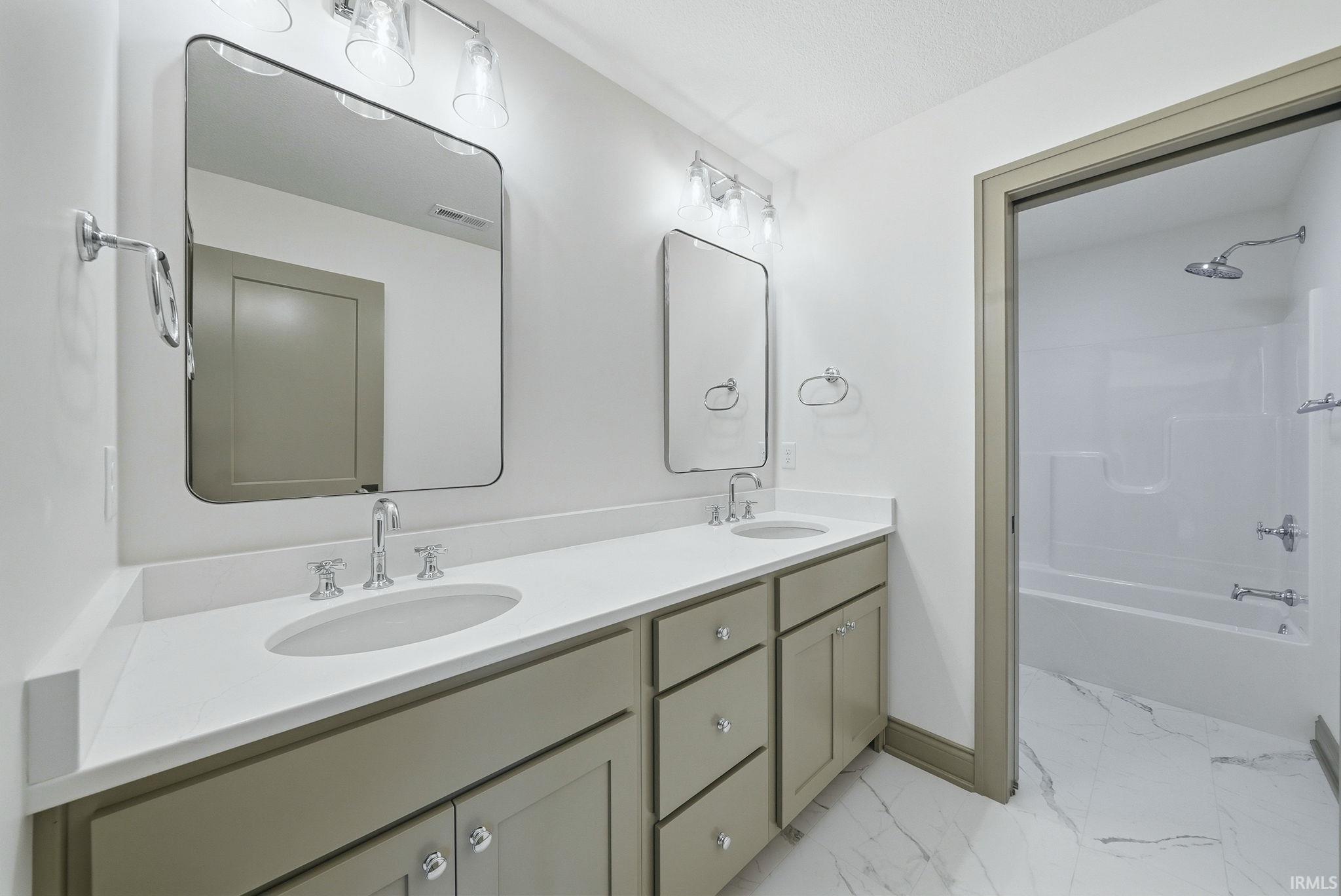 Dual vanity featuring light-toned cabinetry, polished chrome fixtures, and white countertops