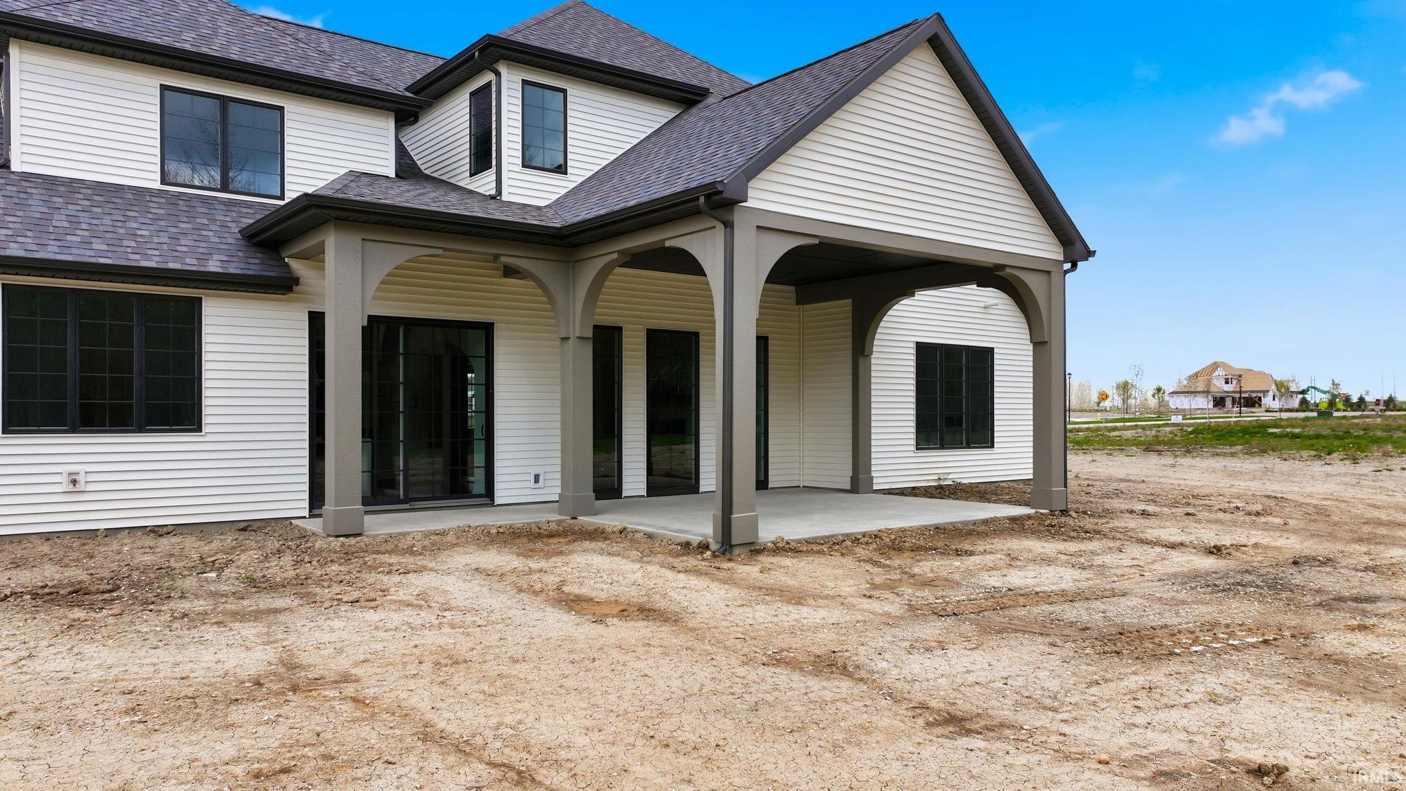 Covered patio with concrete flooring, supported by architectural columns with arched detailing