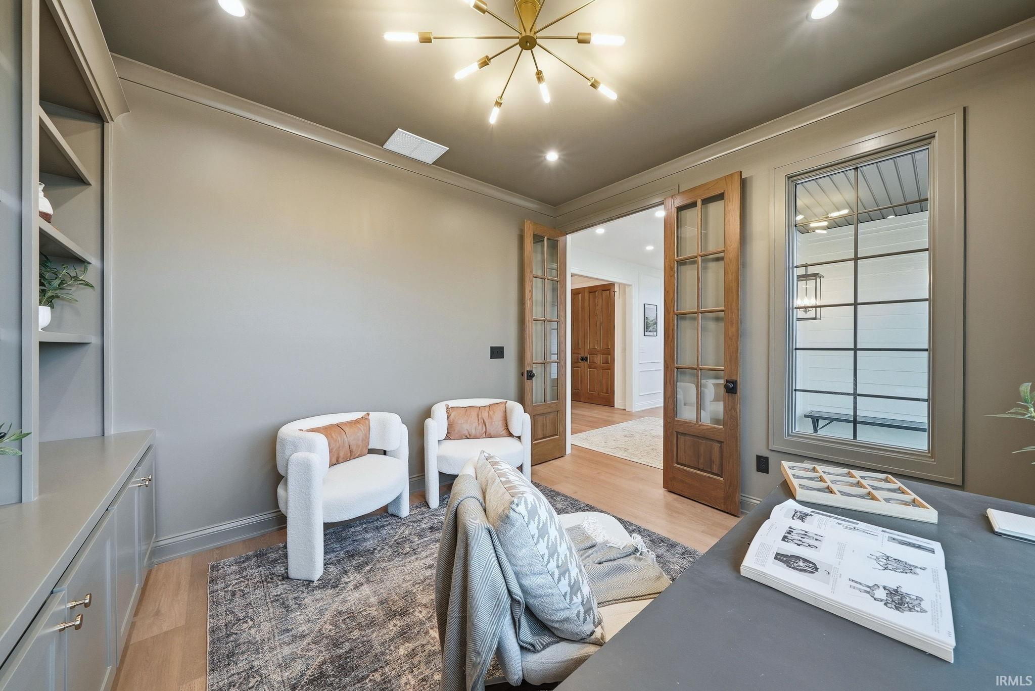 Interior space featuring a built-in cabinetry and shelving unit, wood-finish flooring, and a contemporary sputnik chandelier