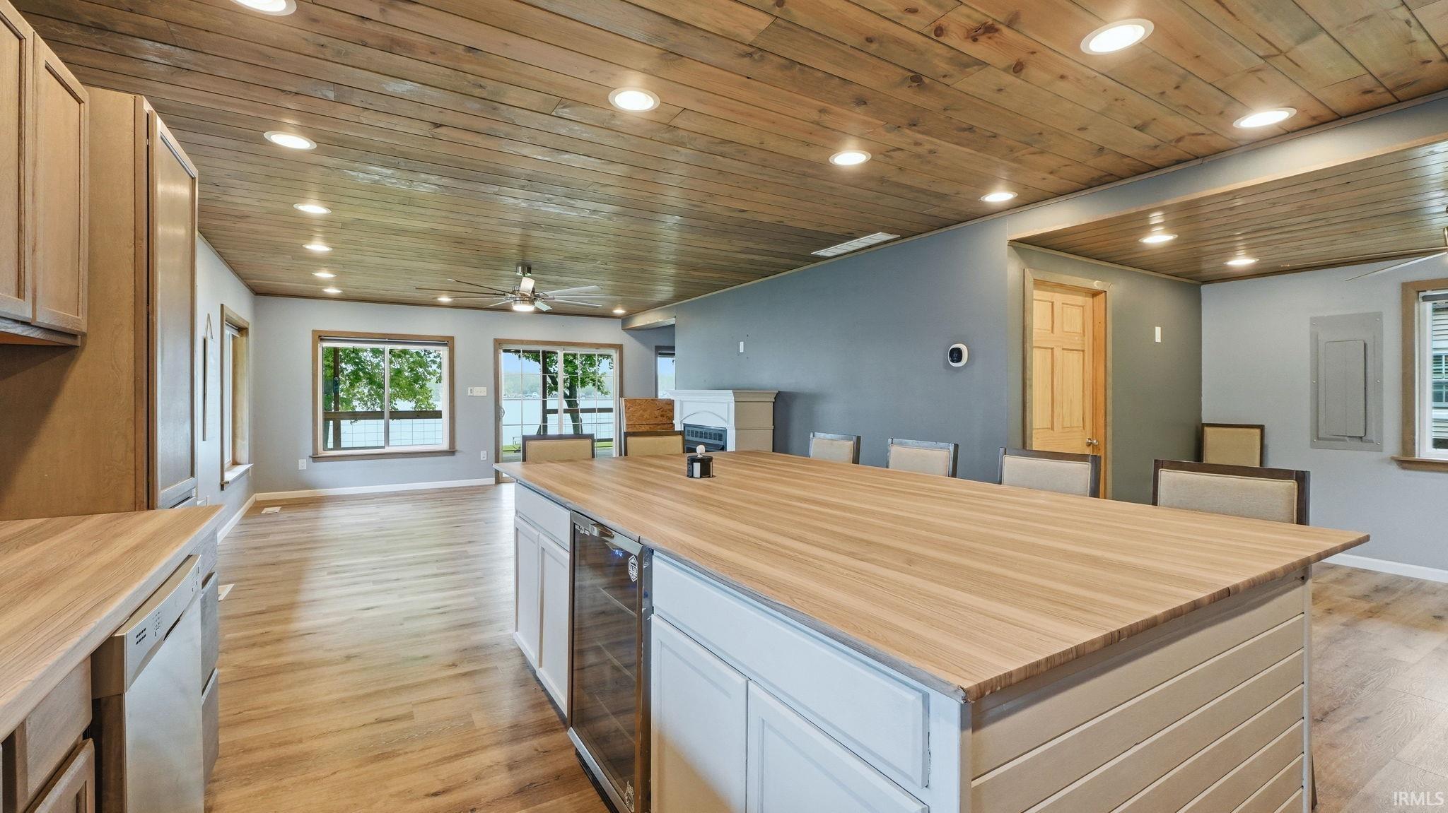 Open-concept living area featuring a wood-panel ceiling with recessed lighting