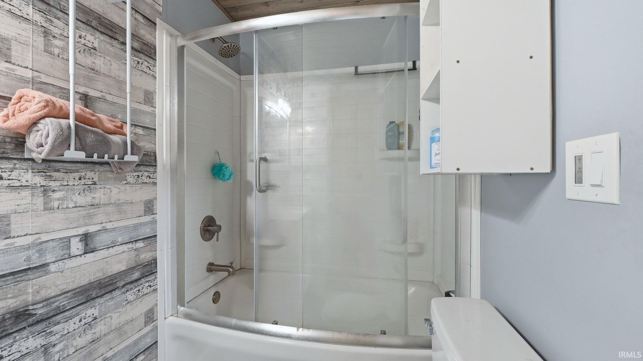 Bathtub with sliding glass enclosure, featuring a brushed nickel showerhead and faucet