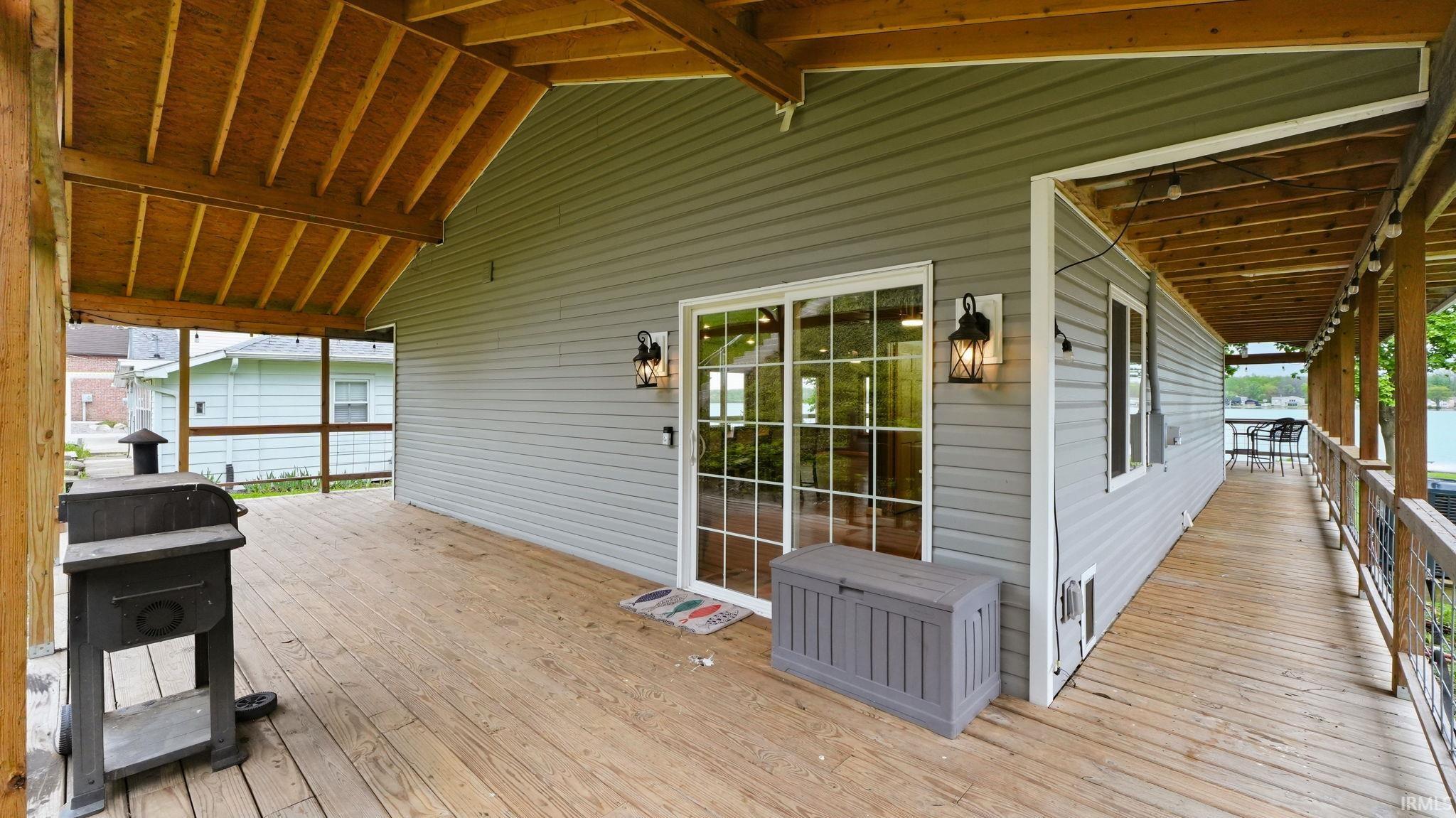 Expansive outdoor deck featuring wood-finish decking, a vaulted wood-finish ceiling, and light gray siding