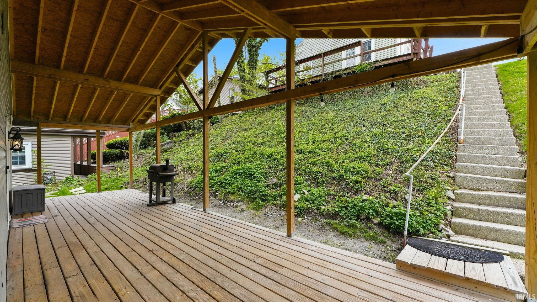 Expansive covered deck with exposed wooden beams and plank flooring