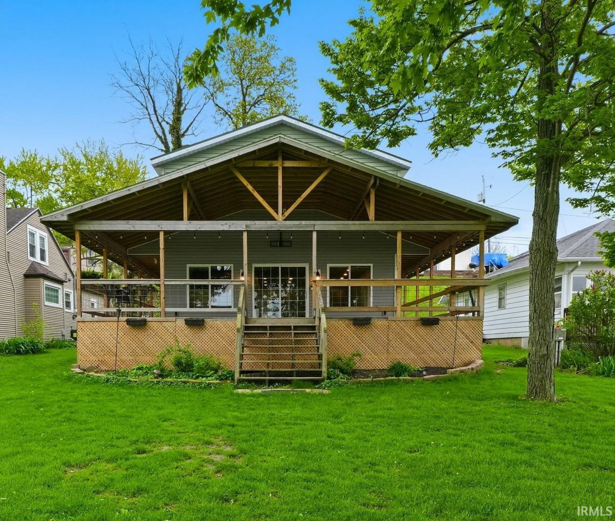 Expansive covered deck featuring exposed wood beams, string lighting, and direct access through a glass slider