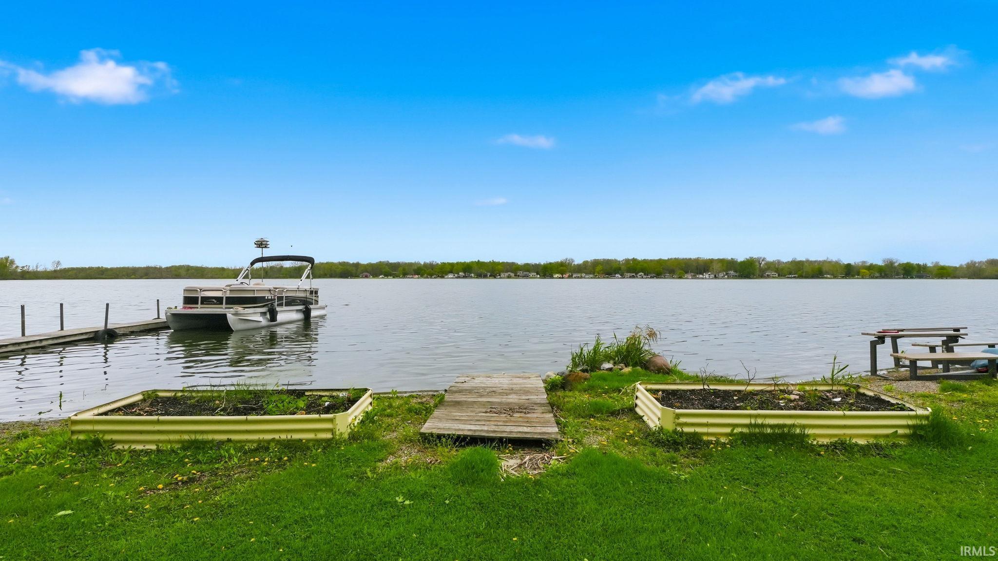 Waterfront setting featuring a private dock, direct water access, and two raised garden beds