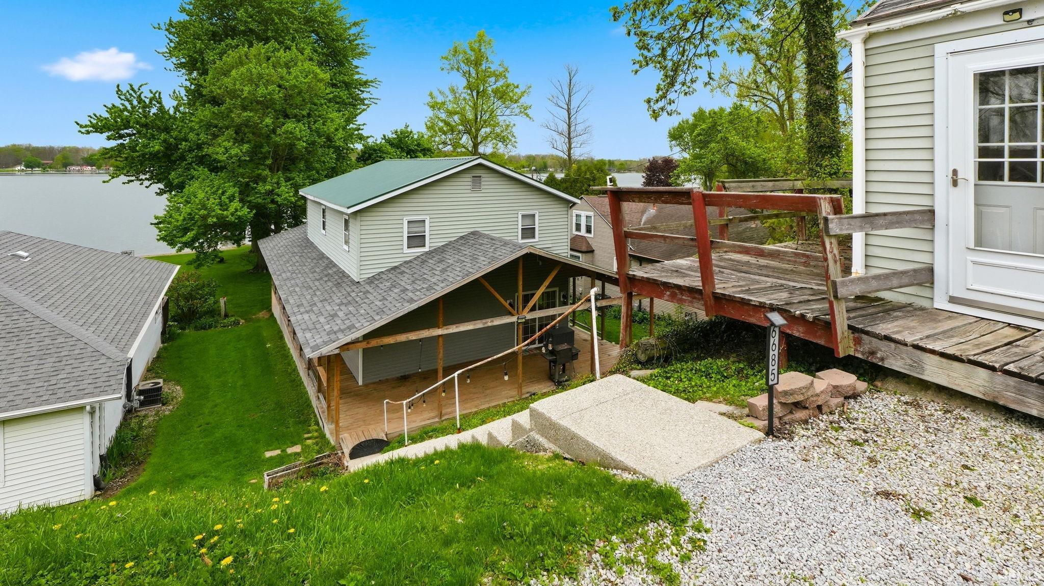 Waterfront property featuring a covered deck with railings, a concrete ramp, and gravel landscaping