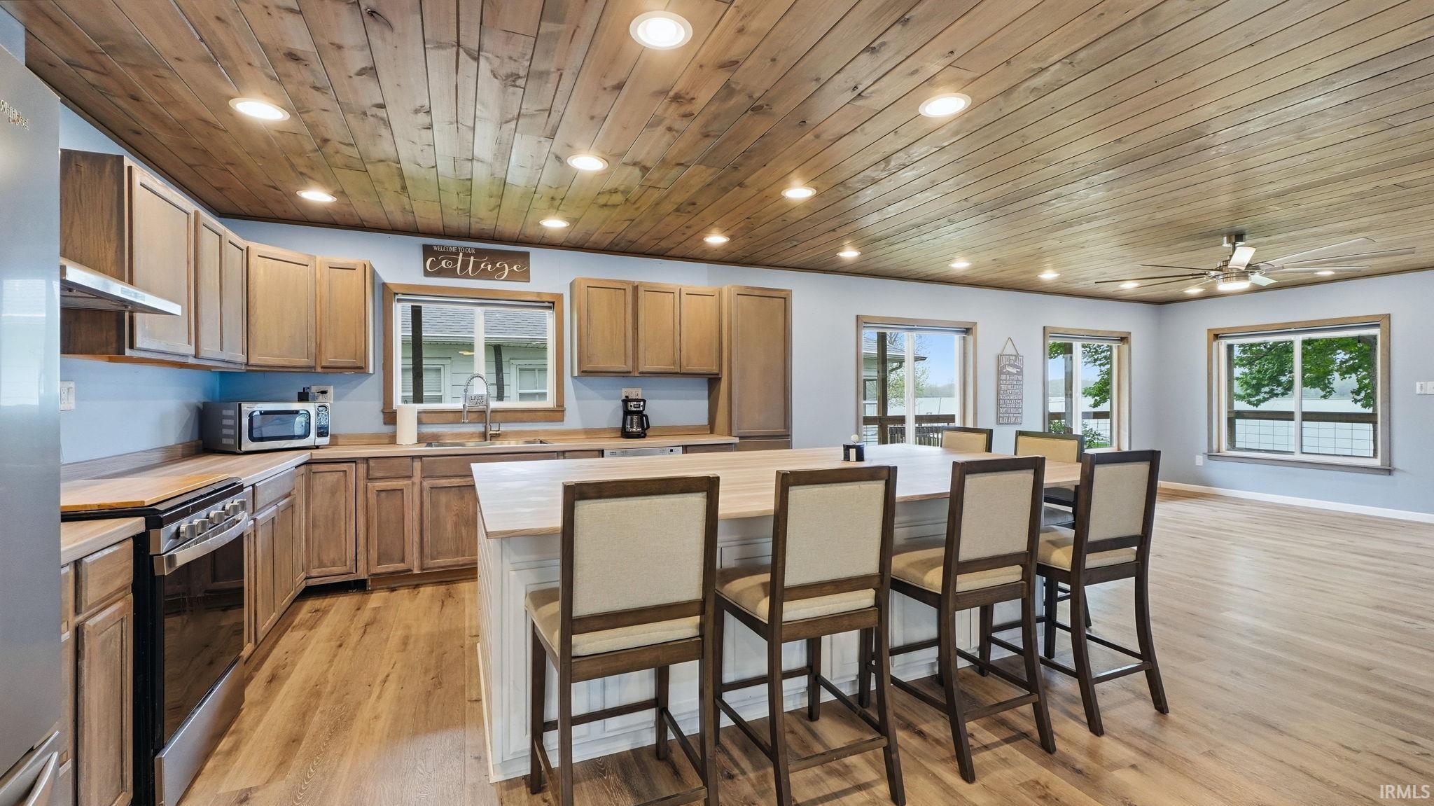 Open-concept kitchen and living area featuring a wood-panel ceiling, recessed lighting, and wood-finish flooring