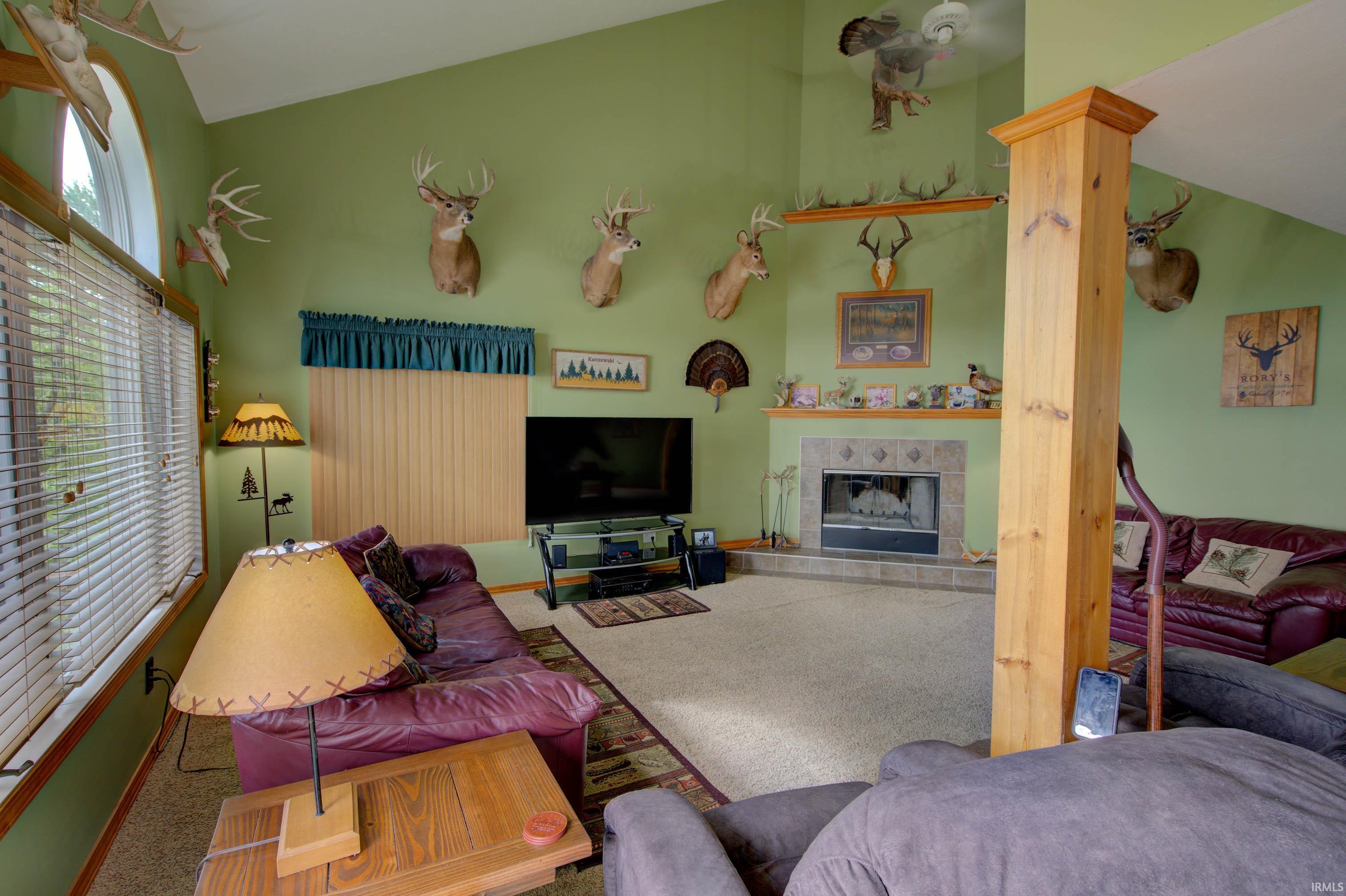Living area featuring a vaulted ceiling and a corner fireplace with a tiled surround