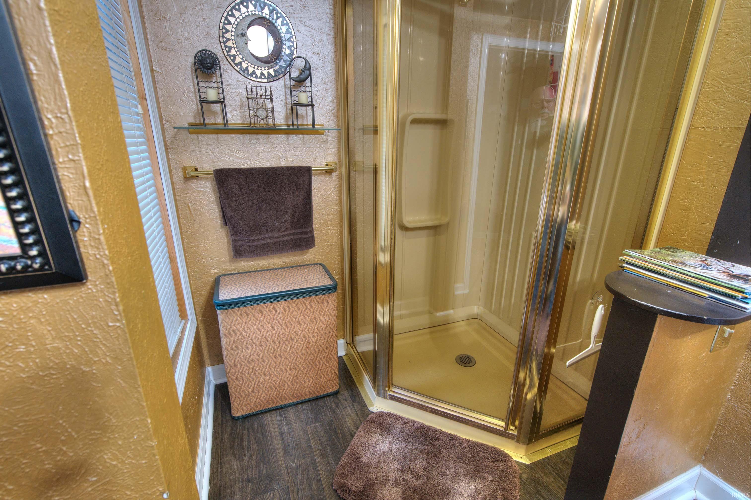 Corner shower enclosure with gold-tone framing and integrated shelving