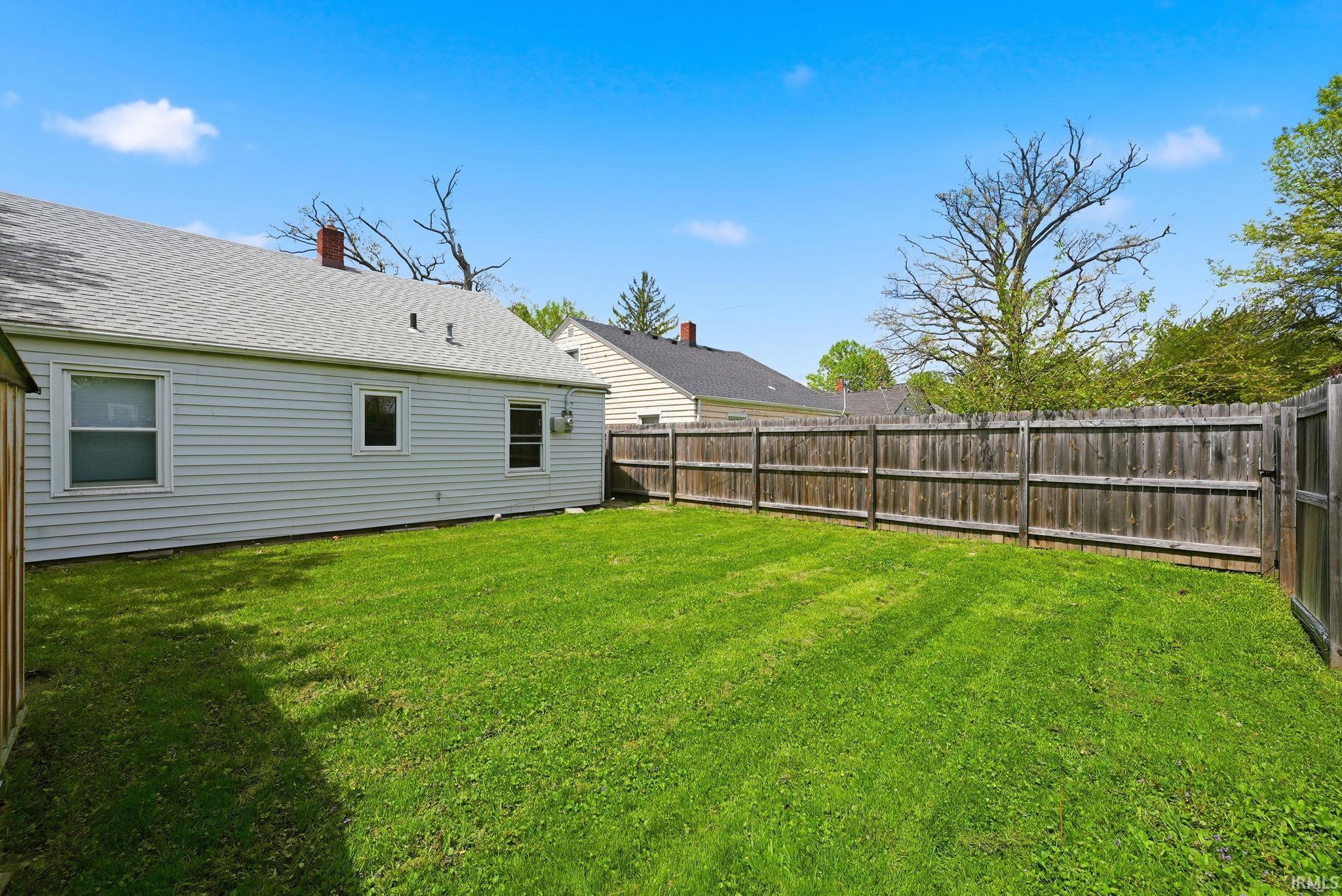 Expansive grass lawn bordered by a wood privacy fence