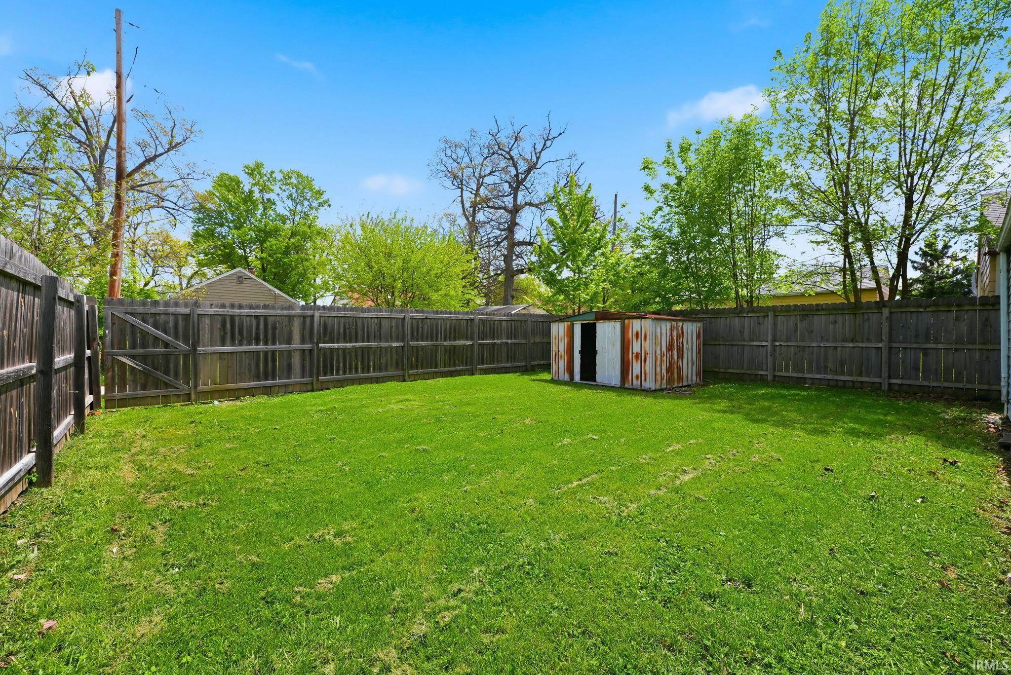Expansive grassy yard area featuring a full perimeter wood fence