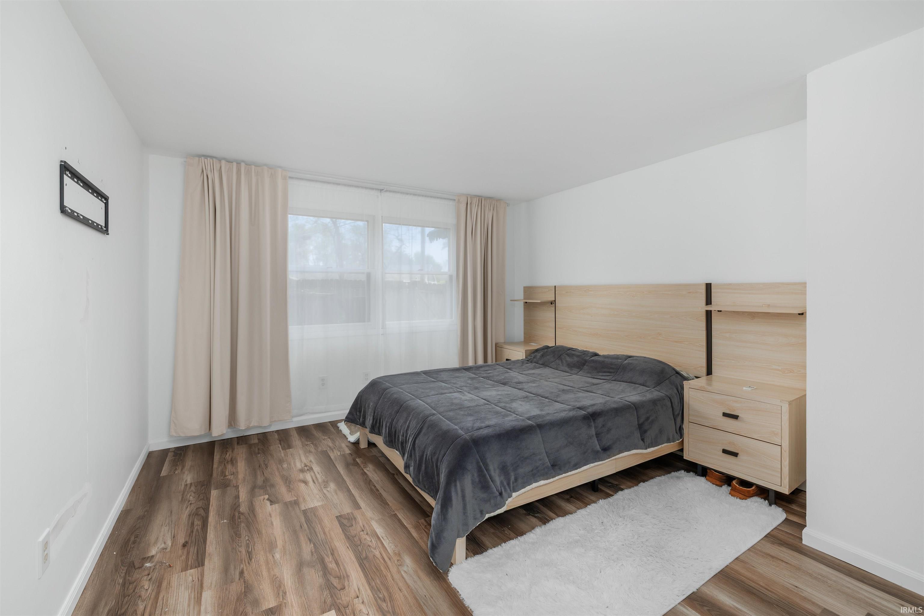 Room with wood-finish flooring, white walls, and a large window
