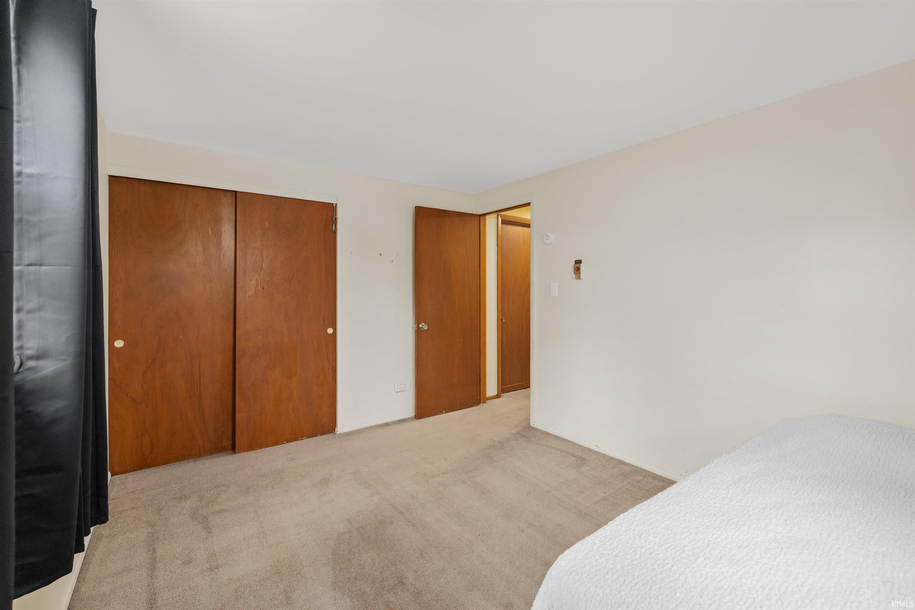 Carpeted interior space featuring two wooden bi-fold doors and a wooden paneled door frame