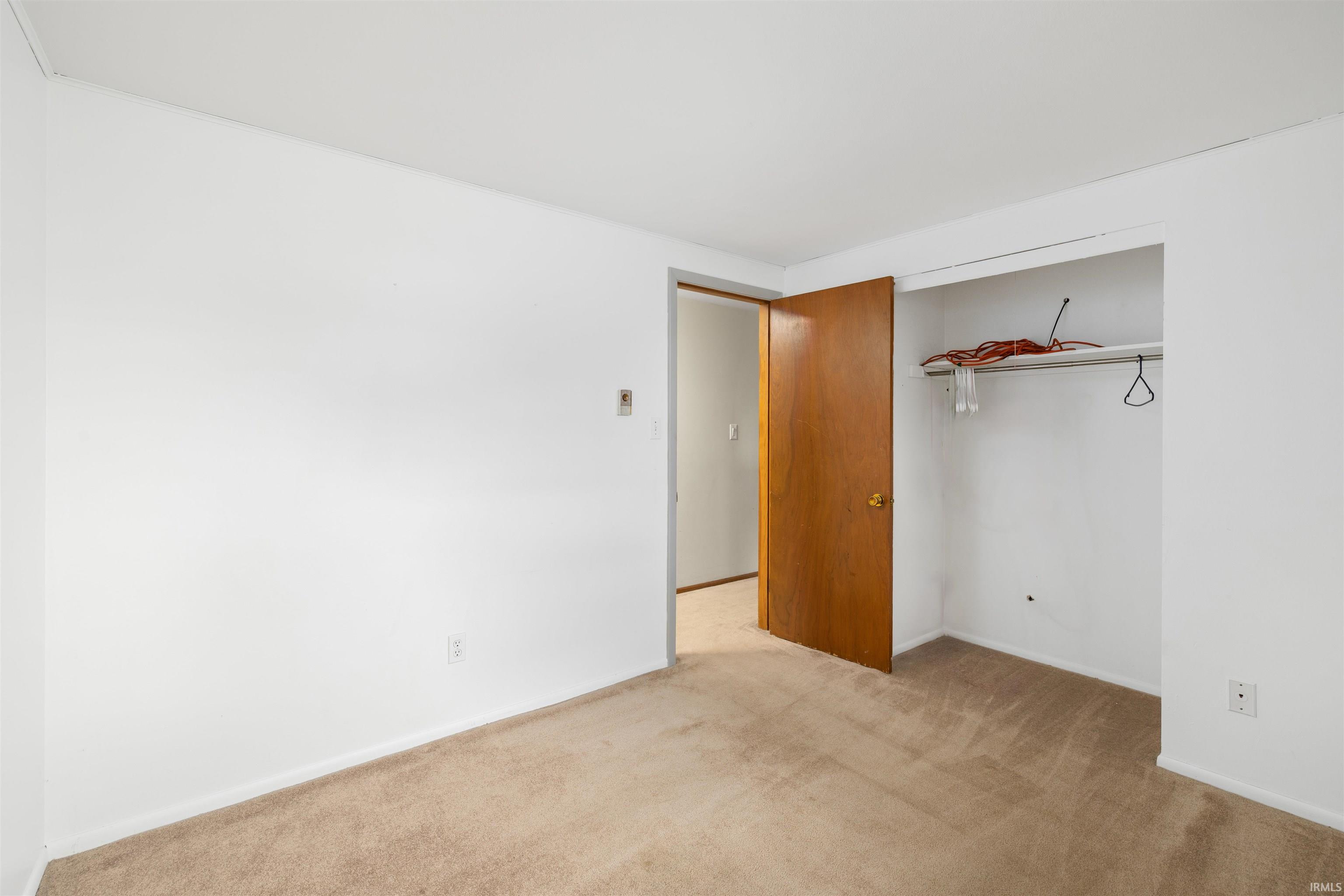 Room featuring neutral wall finishes, carpet flooring, a solid core door, and an integrated closet with a hanging rod