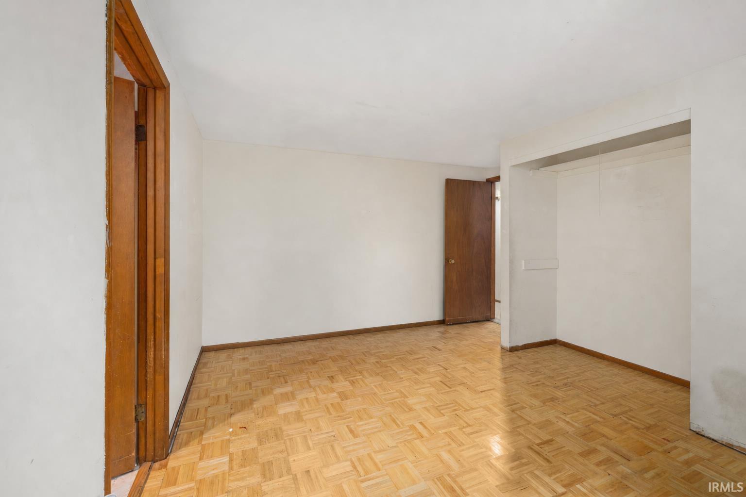 Room featuring parquet wood flooring, white walls, and a recessed opening
