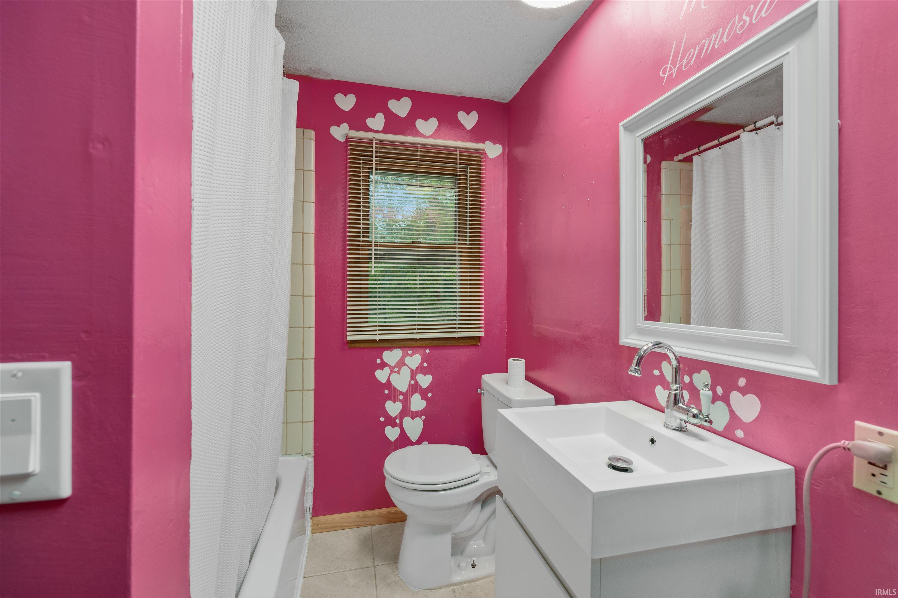 Bathroom featuring a white vanity with integrated sink, chrome faucet, white framed mirror, and a window with blinds