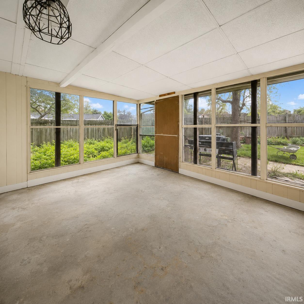 Sunroom featuring concrete flooring, a white paneled ceiling, and multiple window panels providing natural light