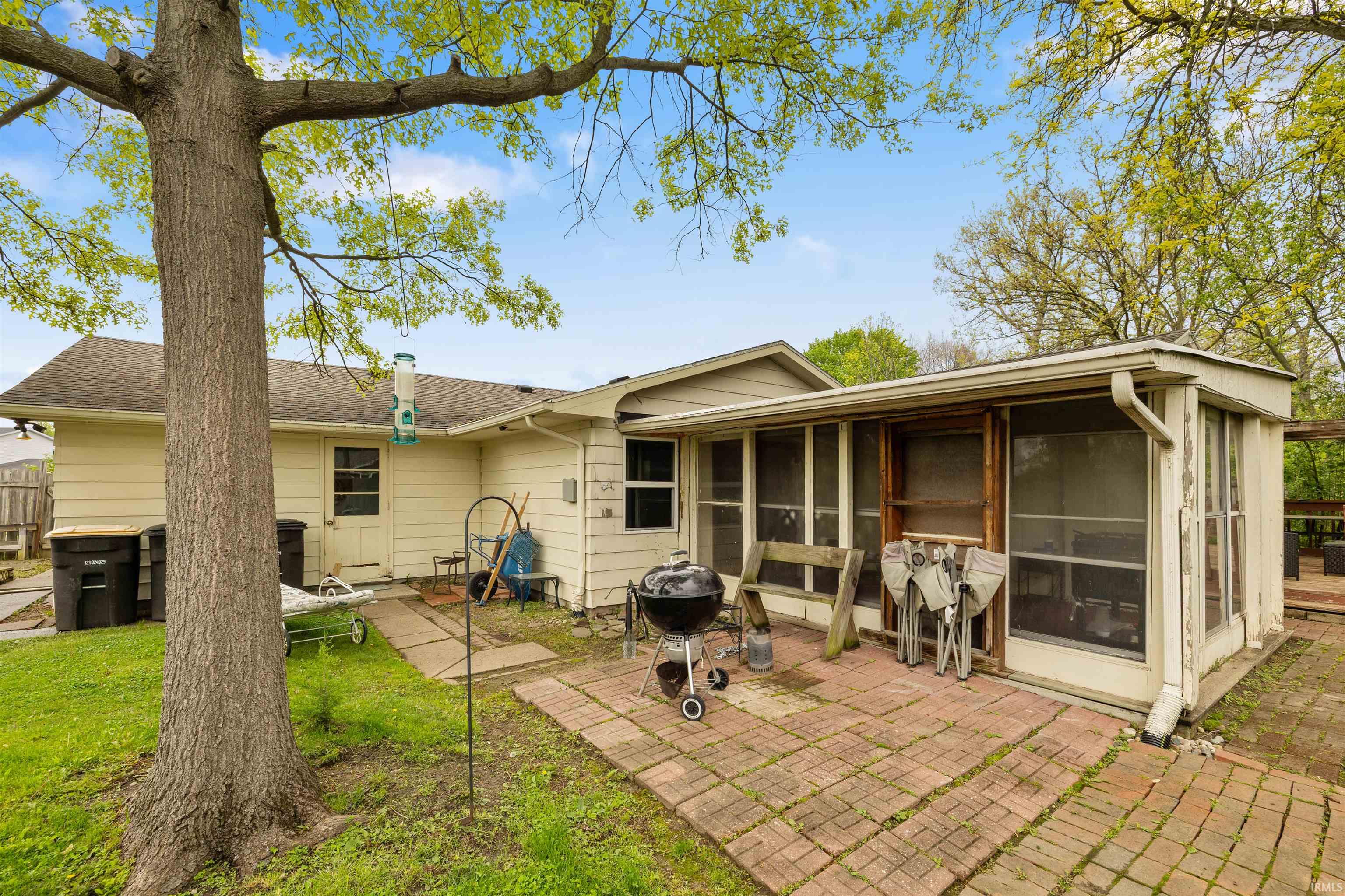 Rear exterior featuring a brick patio and enclosed sunroom