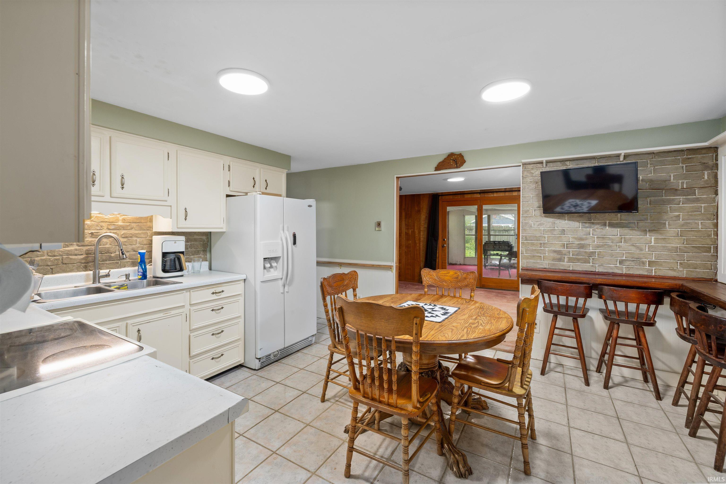 Kitchen featuring light-toned cabinetry, a stainless steel sink, and a tiled backsplash