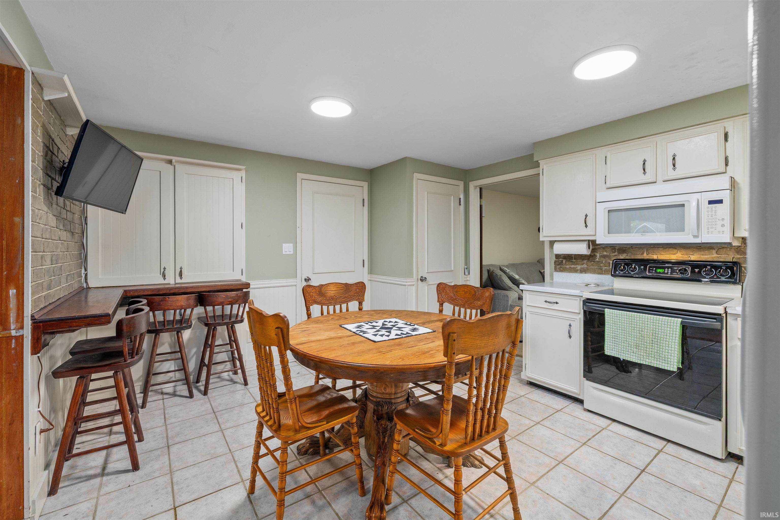 Kitchen featuring white cabinetry, tile flooring, and two ceiling-mounted circular light fixtures