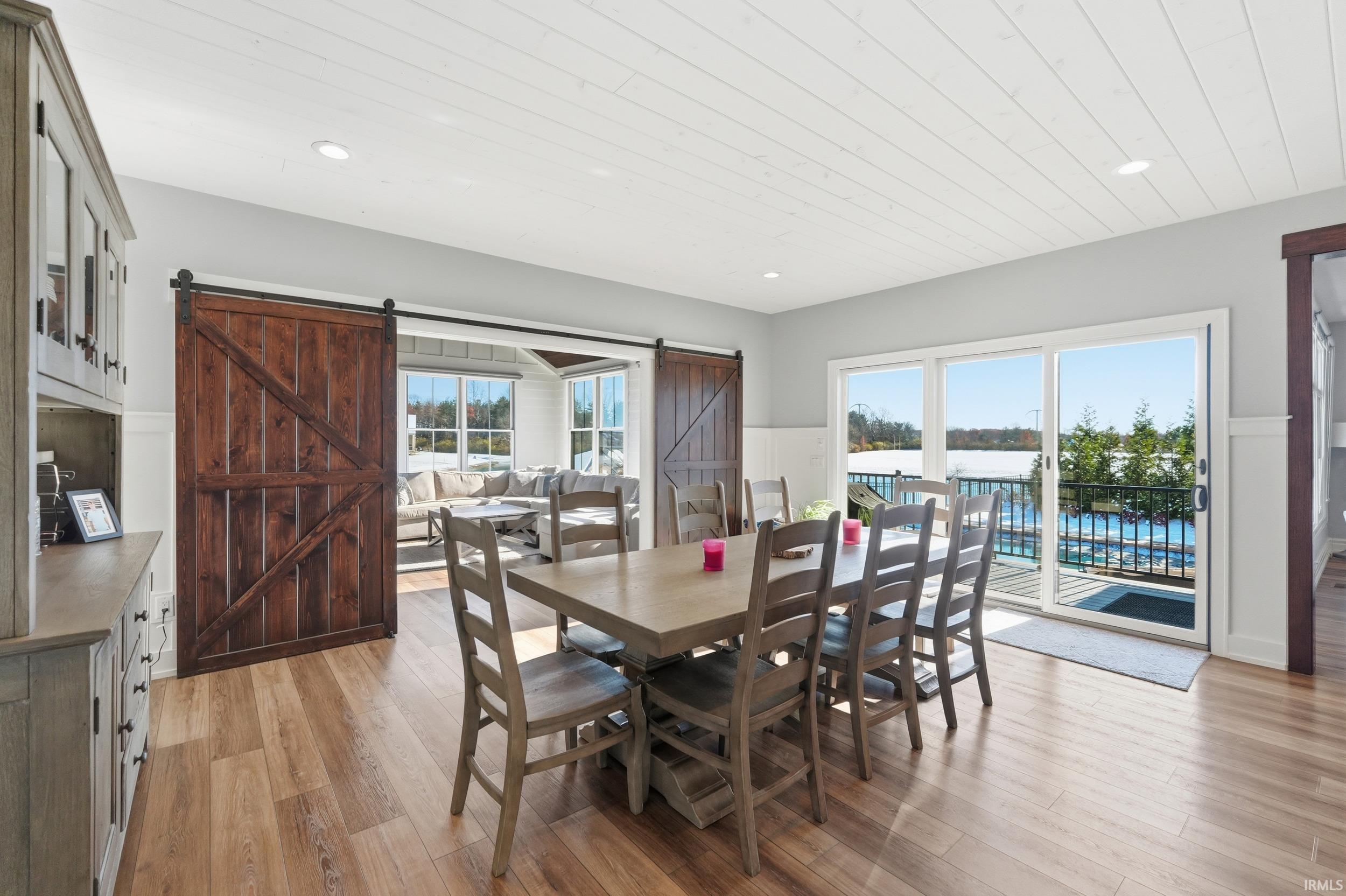 Dining space featuring wood-finish flooring, a planked ceiling, and a built-in sideboard with glass-front upper cabinetry