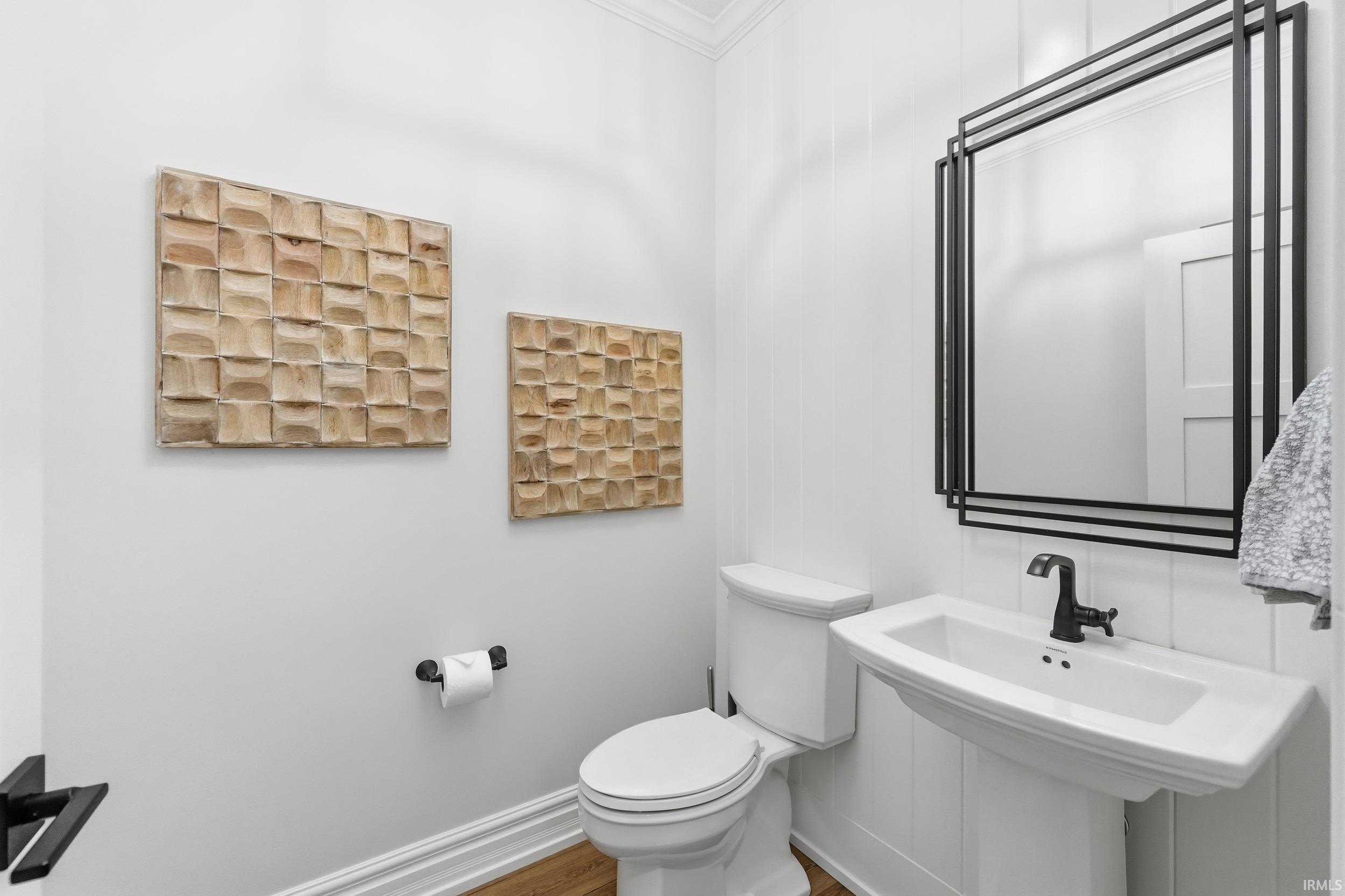 Pedestal sink with matte black faucet, framed by a decorative mirror