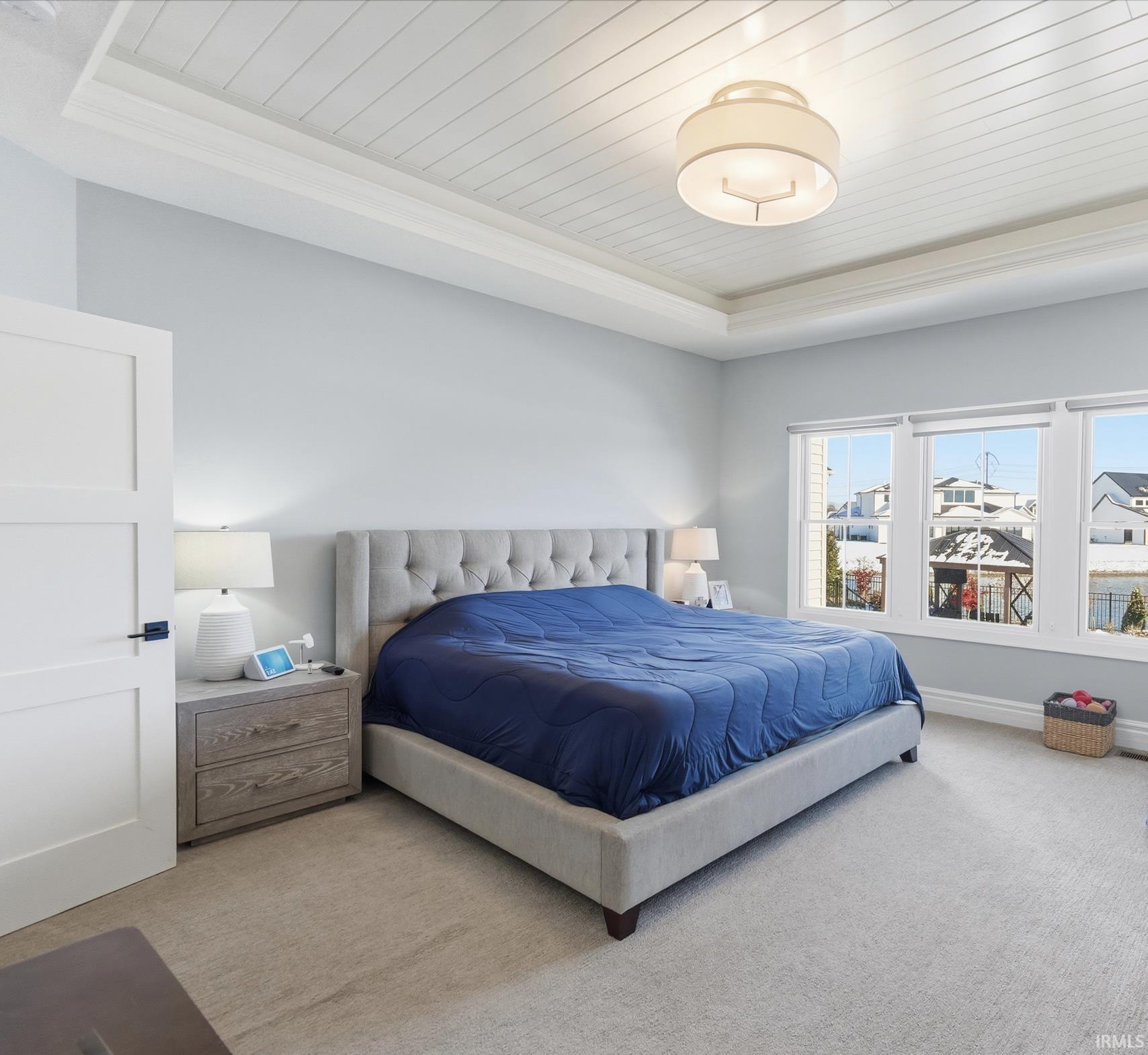 Recessed tray ceiling with white plank detailing, light gray walls, and light-toned carpeting