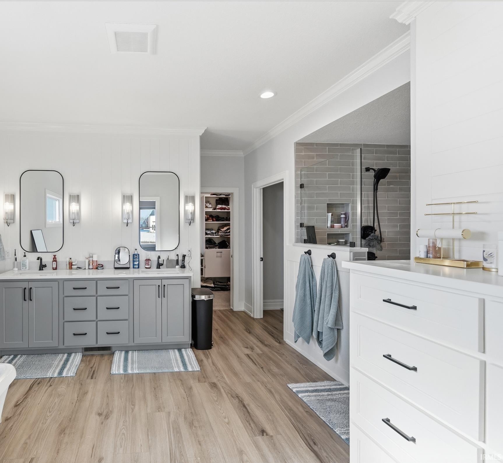 Spacious bathroom featuring wood-finish flooring and a dual vanity with grey cabinetry and white countertops