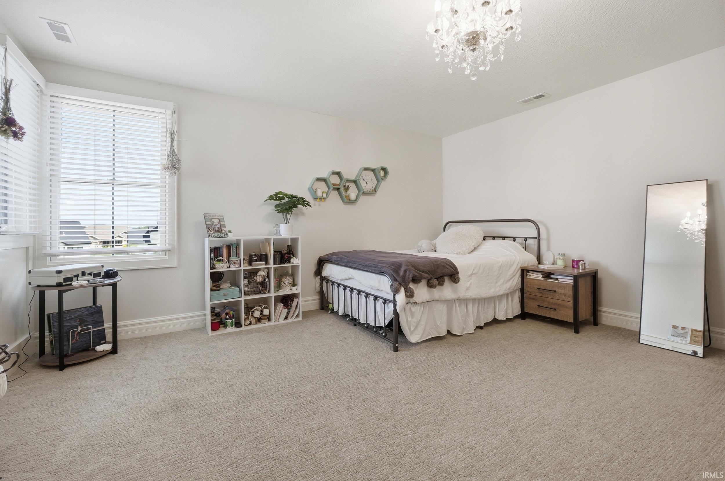Bright bedroom with neutral wall tones and light-toned carpeting