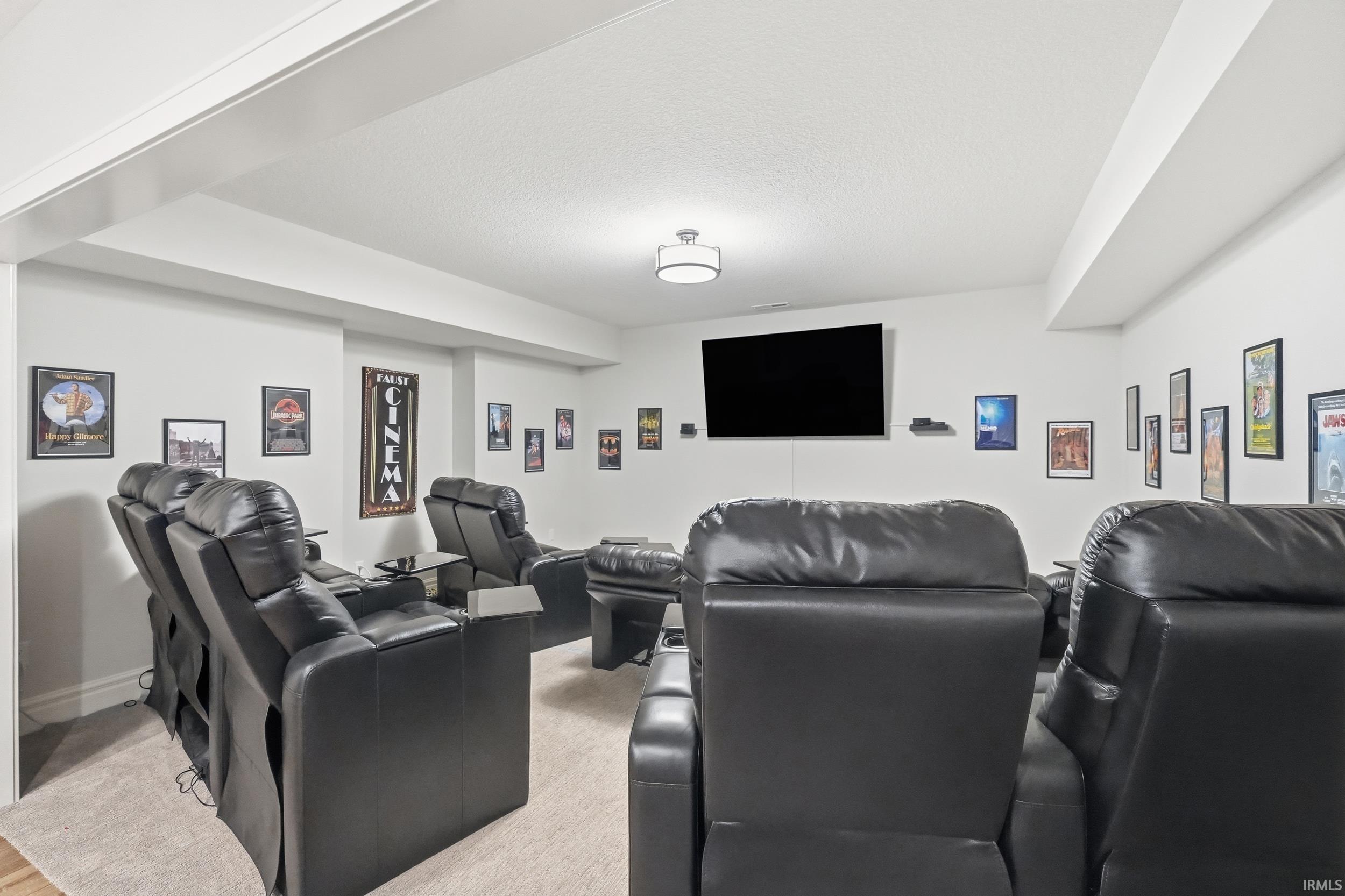 Dedicated entertainment space featuring a wall-mounted display, recessed ceiling, and light-toned carpeting