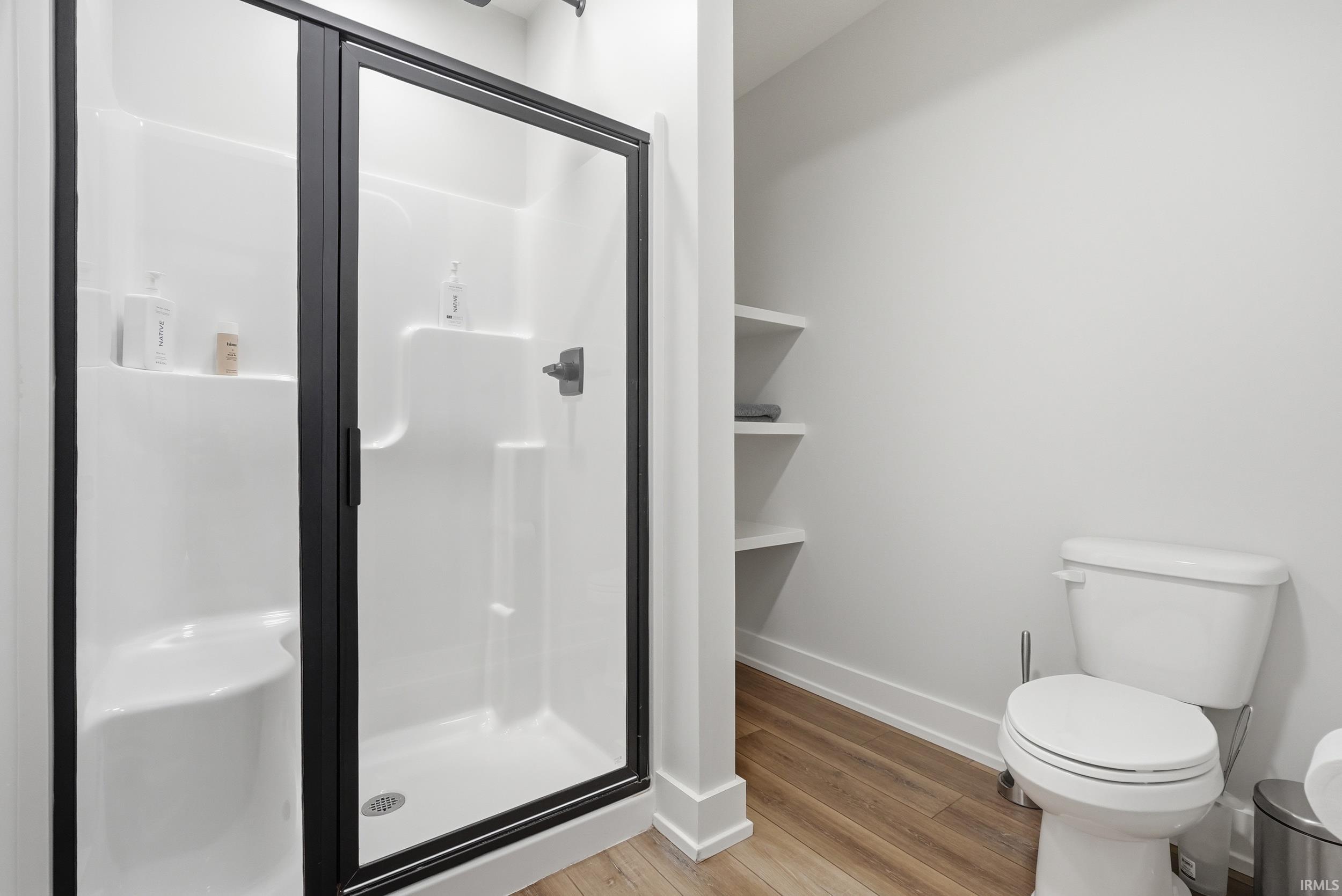 Enclosed shower with matte black framing, integrated shelving, and a built-in bench