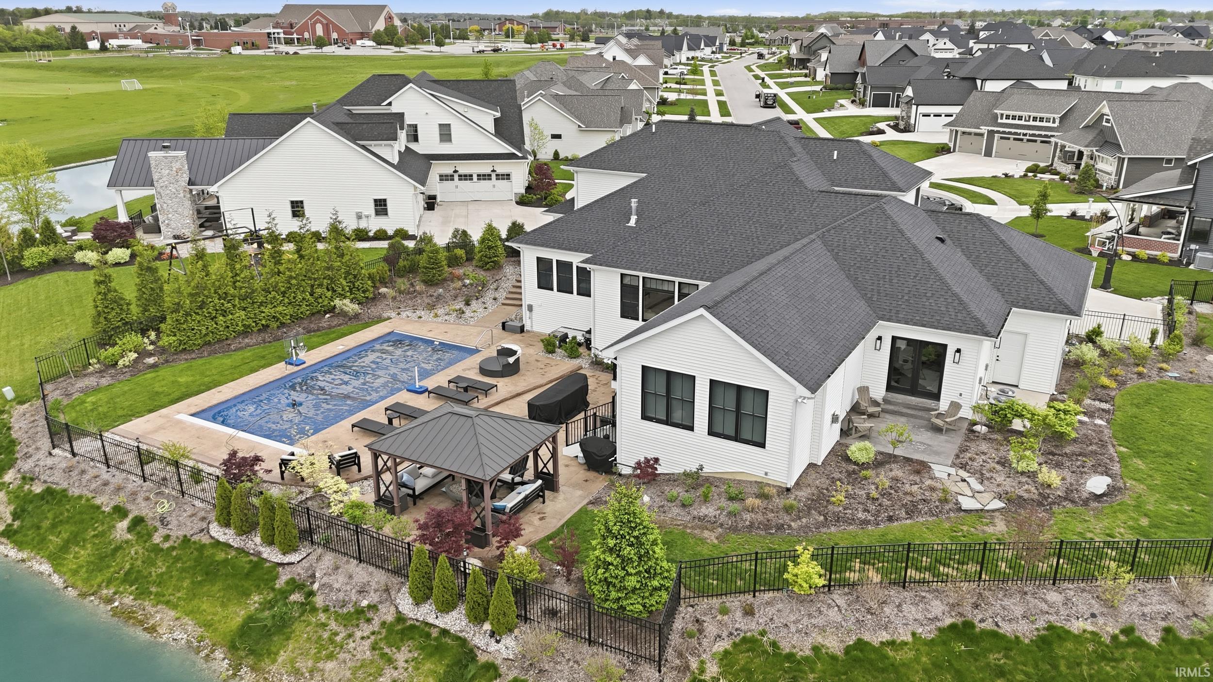 Rear exterior featuring a covered swimming pool, paved patio, and a gazebo