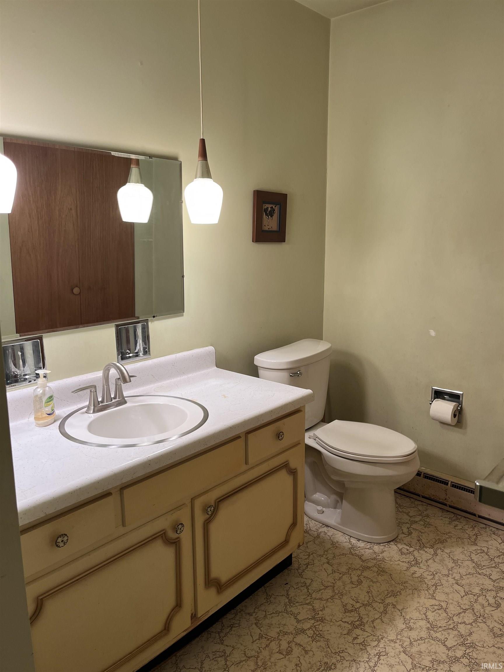 Bathroom vanity featuring a white countertop with an integrated sink, a brushed nickel faucet, and a patterned gold-trimmed cabinet