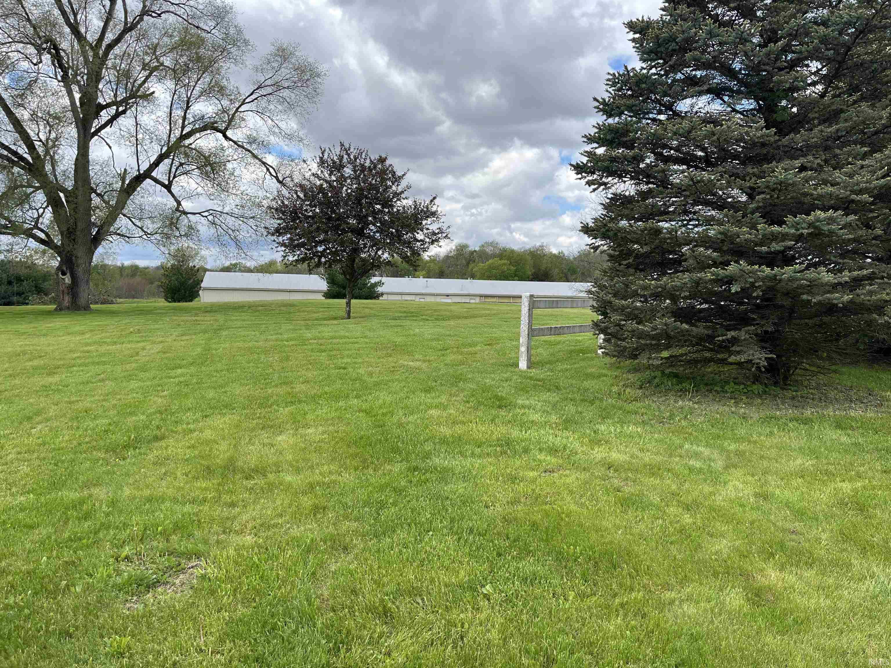 Expansive green lawn with mature trees and a partial wooden fence