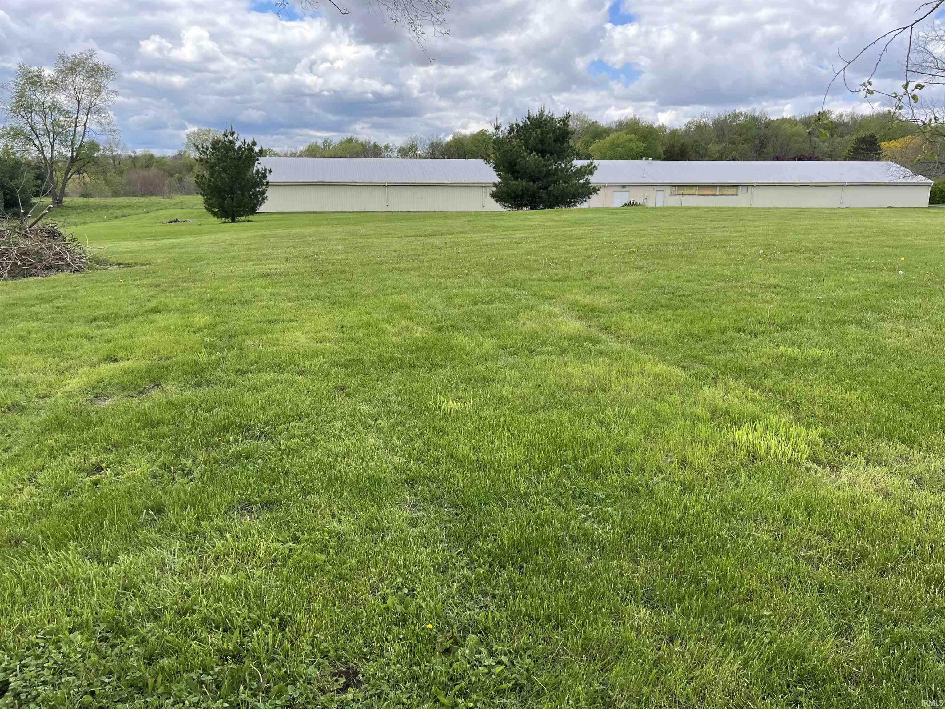 Expansive green lawn with a large building featuring a metal roof and light-colored siding