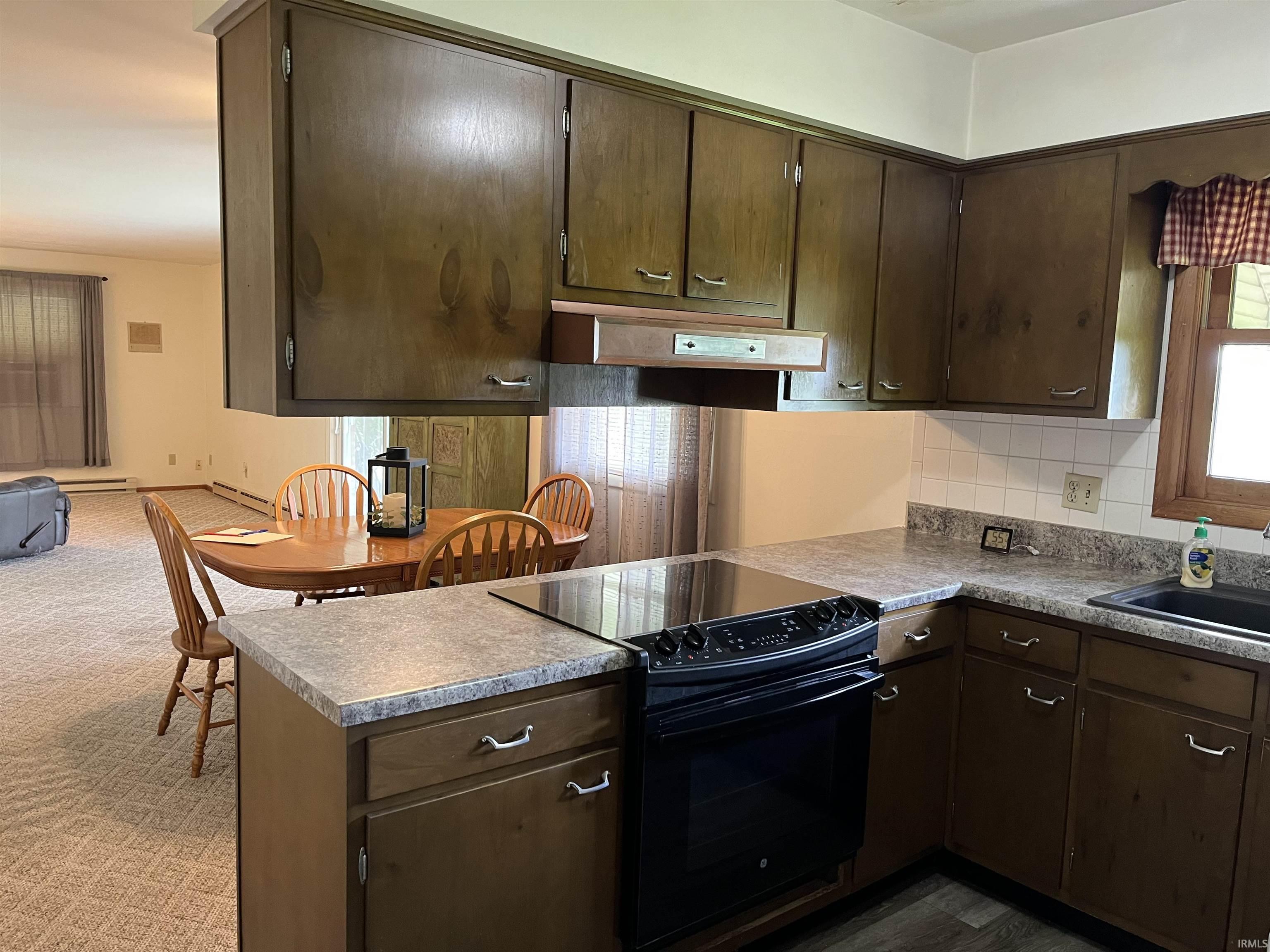 Kitchen featuring wood-finish cabinetry, built-in electric range, and a dual-basin sink