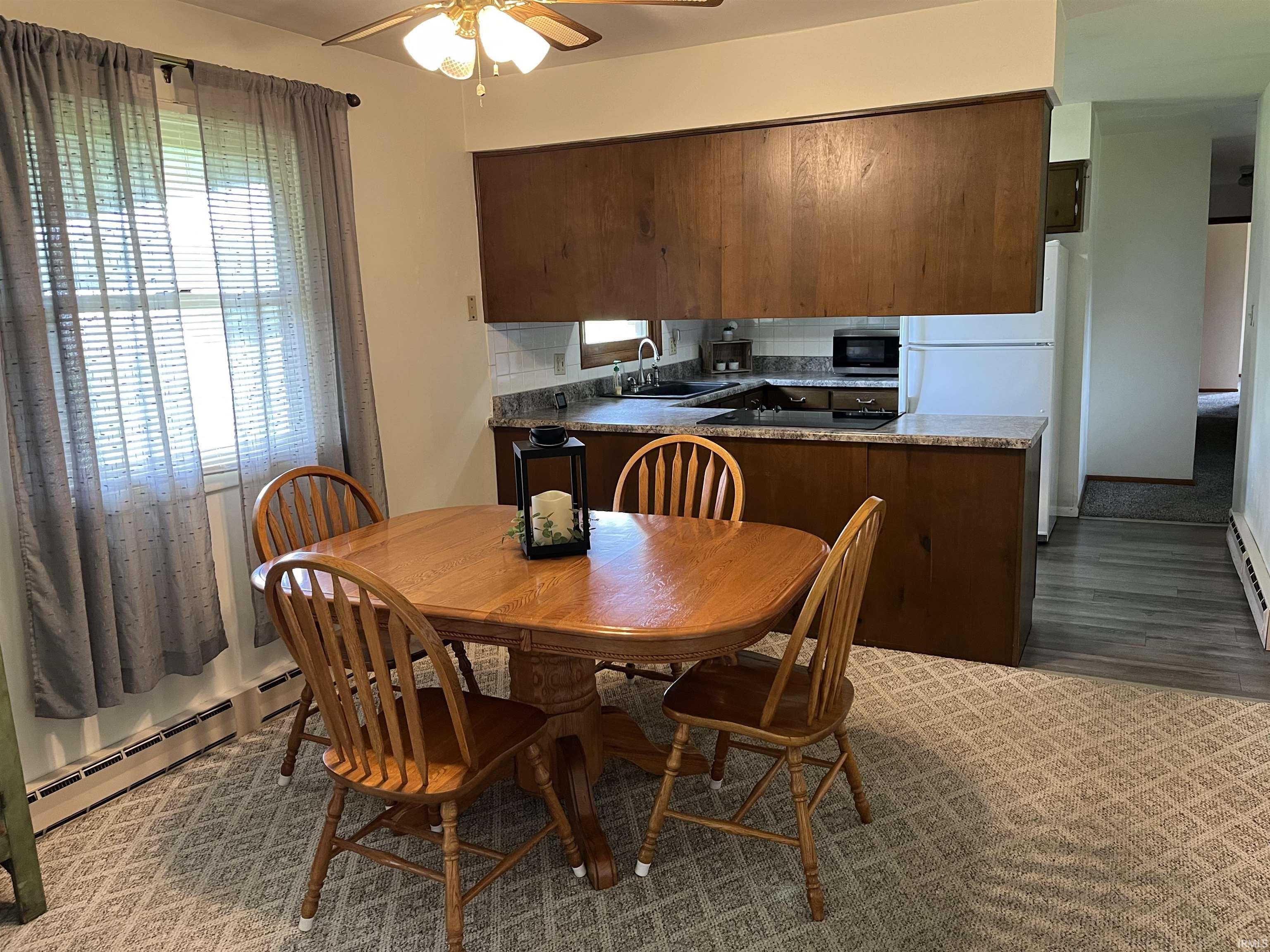 Kitchen area featuring wood cabinetry, stone-look countertops, and a tile-look backsplash